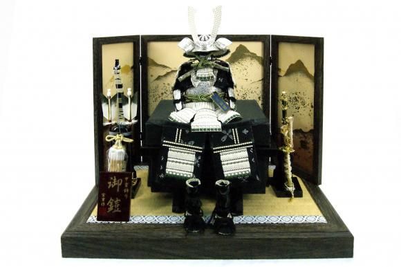 コンパクト　宮冑作　5号銀色鎧飾り 間口60cm　奥行き37cm　高さ45cm 展示品です。 小さな5号銀色鎧です。銀小札に正絹白糸で縅で仕立て上げ、お屏風、飾り台は焼桐に三景柄です。コンパクトながら豪華で綺麗なお飾りです。お値打ち品です。