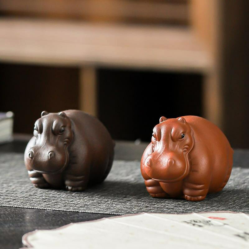 紫砂カバ置物 茶席飾り 約8cm お茶の時間に遊び心を添える、カバモチーフの小さな茶席置物です。茶席や茶室の卓上に置きやすい約8cmサイズで、急須や湯のみと合わせて楽しめます。シンプルで落ち着いた佇まいは、性別を問わず使いやすいインテリアとしてもおすすめです。 紫砂素材を高温焼成し、手仕上げで形を整えています。お茶をかけて使うことで、表面の風合いが時間とともに変化する場合があり、日々のティータイムとともに育てる楽しみを味わえます。紫泥と朱泥の全2種類からお選びいただけます。 ■ 商品の特徴 カバをモチーフにした、表情のある動物オブジェです。 紫砂素材を高温焼成して成形した焼き物です。 手仕上げで形を整えているため、表面やフォルムに手作りの個体差があります。 お茶をかけて使うことができ、長く使うことで表面の風合いが変化する場合があります。 紫泥と朱泥の全2種類を用意しています。 直径約8cm、高さ約5.5cm、幅約5.5cmの卓上サイズです。 急須や湯のみなどの茶器と組み合わせやすい茶席飾りです。 ■ 仕様 紫泥 | 朱泥 ■ 仕様 素材紫砂（陶磁器素材の記載もあります） 製法高温焼成、手仕上げ サイズ直径約8cm、高さ約5.5cm、幅約5.5cm 仕様カバモチーフ、紫泥・朱泥の全2種類 用途茶席、茶卓、茶室の装飾 使用方法お茶をかけて使用可能 参考重量約1000g 包装安全包装（詳細は発送時の仕様に準じます） ■ おすすめシーン 急須や湯のみと組み合わせる茶席コーディネートに。 茶卓や茶室の雰囲気づくりに。 日常のティータイムの卓上飾りに。 お茶好きの方への贈り物に。 動物モチーフの卓上オブジェを楽しみたいときに。 ※手作りのため、形状や表面の仕上がりには個体差があります。※サイズは手作業による採寸のため、多少の誤差が生じる場合があります。※お茶をかけて使用した後は水分を拭き取り、よく乾かしてください。※強い衝撃を与えると破損するおそれがあります。※素材・産地の表記は商品情報内で異なるため、購入前にご確認ください。※モニター環境により実物と色味が異なる場合があります。