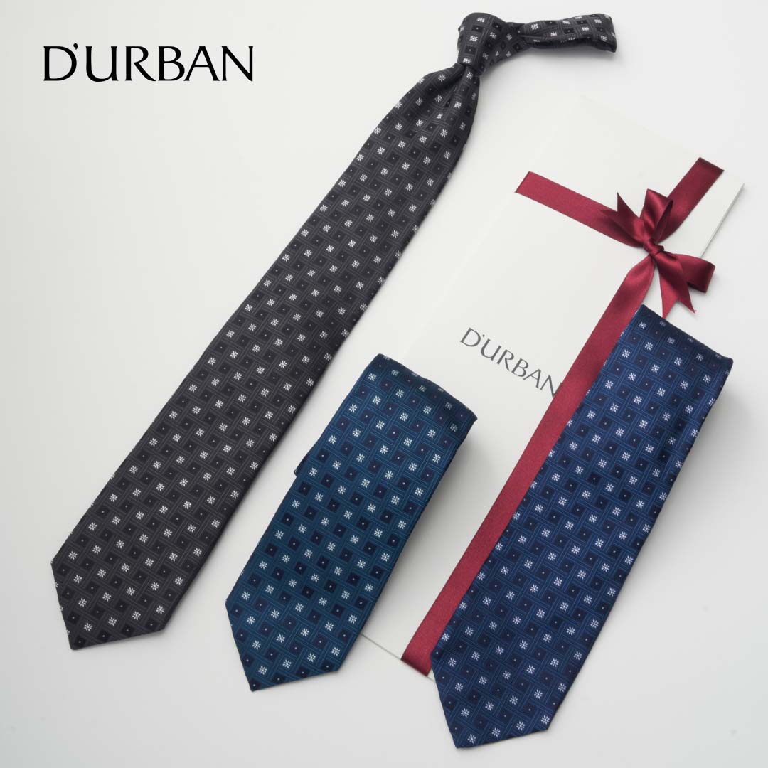 D'URBAN HACHIOJI 小紋（八王子織）ネクタイ 日本のビジネスシーンを牽引する、大人の信頼と品格を贈る一本。 　遠目には無地に見え、近づくと繊細な織り柄が浮かび上がる、クラシックな小紋柄のネクタイです。希少価値の高いMADE IN TOKYO「八王子織」ならではの、奥行きのある美しい質感が特徴。江戸時代から続く「甲斐絹」をルーツとする高い技術が、Vゾーンに知性と個性をさりげなく演出します。日本のビジネスマンを50年以上支え続けてきたダーバンが贈る、まさに「大人のための」特別な一本。新たな一歩を踏み出す方への、確かな信頼を形にしたギフトに最適です。 商品詳細 品番： 105015203 価格： 11,000円（税込） スタイル： 八王子織 小紋柄 サイズ： 大剣幅: 8.0cm ／ 全長: 143cm 素材： シルク100% 原産国： 日本（東京都 八王子織） 選べる純正パッケージ お客様のお好みに合わせて、2種類のブランドロゴ入りパッケージからお選びいただけます。 ■ タトウ紙： 一目でネクタイと分かり、スマートで厚みのない洗練された封筒型パッケージ。 ■ キューブボックス： 開けるまで中身が分からず、コロンとしたフォルムが可愛らしい立体パッケージ。 贈る方のイメージやご自身のお好みに合わせて、プルダウンメニューよりご希望のタイプをご指定ください。 DEAR GE YONE SERVICES 贈るときにも、自分のためにも、「ここで選んでよかった」と思っていただける場所へ 【配送について】 お昼12:00までのご注文完了で当日発送いたします（土日祝・休業日を除く）。大切な日の贈り物に間に合うよう、丁寧な梱包でお届けします。 【特別なラッピングサービス】 ブランド純正パッケージにお入れし、無料ラッピングではリボンの色が選べるほか、高級感を高める「シーリングスタンプ（まつぼっくり）」も選択可能です。 【レビュー投稿でクーポンプレゼント】 商品到着後にレビューをご投稿いただいた方全員に、次回使える【500円分クーポン】をプレゼントしております。