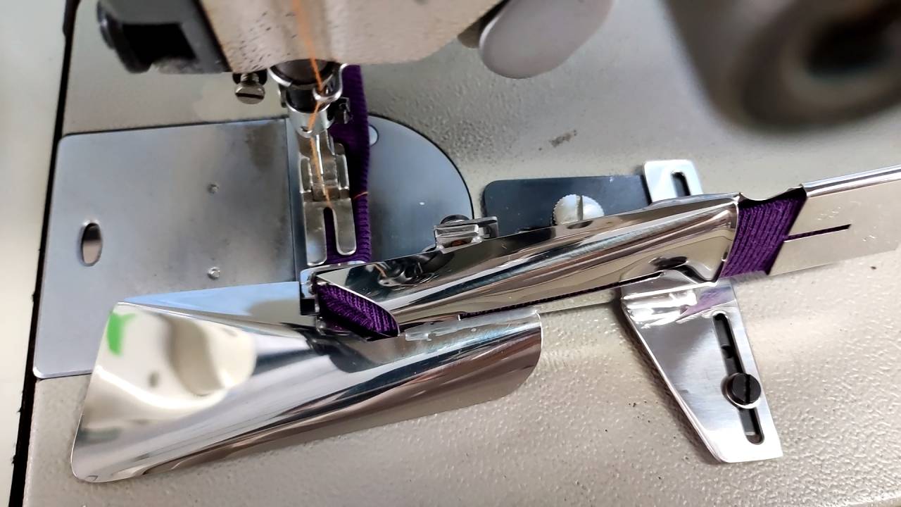 各ミシンメーカー一本針本縫いミシン　婦人服、子供服、小物商品の縁巻飾りとして利用できます。　適応素材：ジャワラテープ、ニット編テープ等伸縮性のテープにて縫製します。　ミシンベッドへネジ止め式ですので、針板、送り歯の取り替え不要。　上下左右の位置調節可
