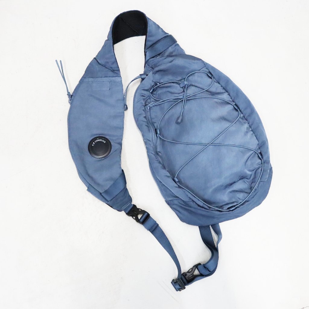 ■DESCRIPTION■【C.P. COMPANY国内正規取扱店】ミリタリー風の光沢あるナイロンサテン「Nylon B」を使用したクロスボディリュックサック。バックル留めの調節可能なストラップ、背面のジッパーポケットとマジックテープポケット、ジッパーポケット、そしてロゴをあしらった内側のスナップボタン付きポケットを備えています。このアイテムはガーメントダイ加工が施されており、独特の色合いを実現し、使い込むにつれてその色合いが深まります。このアイテムのレンズは、新しいマット仕上げのデザインを採用しており、2026年Fall/Winterコレクションから導入されたNFC (近距離無線通信) 技術が組み込まれています。スマートフォンでタップするだけで「プロダクト・パスポート」が開き、そのアイテムに関する情報にアクセスできます。また、内側のラベルにあるQRコードをスキャンしても「プロダクト・パスポート」にアクセスできます。 バックル留め付き調節可能ストラップ 背面ジッパーポケットおよびマジックテープポケット ジッパーポケット レンズディテール ロゴディテール付き内側スナップポケット ガーメントダイ前面携帯収納：H18cm (ファスナー口)×W8cm (H16×W8×D1の大きめの携帯電話も収納可能)※レンズ部分に貼付されているNFCマークは保護シールです。シールを剥がすと、C.P. Companyのロゴのみが残る仕様となっています。【同一商品の掲載で価格が異なる場合について】海外生産品や原材料・為替等の影響により、継続商品でもシーズンごとに価格が改定される場合がございます。そのため、同一商品でも販売時期により価格が異なる場合がございますが、旧価格の商品は当時の価格のまま販売しております。なお、メーカーによる価格改定があった場合は、当店でも順次新価格へ変更となります。その際、商品に付いているプライスタグが改定前の価格表記となっている場合がございますので、あらかじめご了承ください。価格改定前の商品は在庫限りとなり、完売後は新価格での販売となります。また、販売時期によって一部仕様が変更されている場合がございます。旧価格の商品はお求めやすい価格となっておりますので、ぜひお早めにお求めくださいませ。■MODEL■---■MATERIAL■素材：NYLON 100%裏地：POLYESTER 100%別布：POLYESTER 100%■SIZE SPEC■[ONE] 縦：33cm 横：19cm マチ：8cm■ATTENTION■・製品加工や生地の特性により、同一商品であっても記載寸法に多少の誤差が生じる場合がございます。・商品は在庫品よりご用意しておりますが、展示品をお届けする場合がございます。・ご家庭でお洗濯される際は、縮みや色移りなどに十分ご注意ください。・記載寸法は、当店で実測したサイズ、またはメーカー公式サイズを採用しております。[ご注文について]・ご注文いただいた翌日以降のキャンセルはお断りさせて頂いております。また内容を間違えて注文される方が増えております。ご注文完了する前によくご確認の上、ご注文をお願いいたします。・出荷後のキャンセルはお断りさせていただいております。 ・商品が入る透明袋や薄葉紙はメーカー出荷時のものを利用しておりますが、破損していた場合は当店既定の透明袋に入れ替える場合がございます。(ロゴや品名が記載されている袋も該当します)・高額なご注文やお客様情報が不明な場合はお電話にてご本人確認させていただく場合がございます。また第三者のクレジットカードを使用したクレジットカード詐欺が多発しております。当店のクレジットカード審査によってご連絡させていただくことがございますが、クレジットカード詐欺の被害を阻止するための対応となりますので何卒、ご了承くださいませ。■PRODUCT CODE■21CMAC735A-005269G-26FWP ※この商品に関する電話でのお問い合わせは「059-349-6616」ココロザシまで。NYLON B LENS CROSSBODY RUCKSACK #ORION BLUE 871 [21CMAC735A-005269G-26FWP]