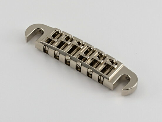 【エービーエム】 ”『ABM3024NA　ラップアラウンド 独立サドルモデル ニッケル（アルミ製）』 アルミ削り出しハンドメイドで制作されるラップアラウンドブリッジです。 通常のラップアラウンドブリッジでは各弦ごとに細かなオクターブ調整をすることはできません。 この独立サドルモデルでは調整可能なサドルを搭載しているため、厳密なオクターブ調整が可能になります。 ラップアラウンド独立サドルモデルはフラット指板に対応します。 ブリッジ本体はアルミの削り出しによって製作されています。 弦の振動をしっかりと楽器へ伝え、楽器本来の響きを一切損なうことなく引き出します。 ■製品概要 　ラップアラウンドブリッジ 独立サドルモデル（アルミ製） 　表面処理：ニッケルめっき ■付属品 　ラップアラウンドブリッジ本体 　スタッド/アンカー（インチ規格） ■材質 　ラップアラウンドブリッジ：アルミ削り出し 　アンカー：ベルブラス削り出し 　スタッド：カーボンスチール削り出し ■製造国 　ドイツ ドイツの老舗パーツブランド「ABM」について ■About ABM ABMは、エレクトリックギターが誕生して間もない1949年に設立されたエレクトリックギターおよびエレクトリックベース用の金属パーツ会社です。 私たちが一番大事にしているのは、パーツによるサスティーンを最大限に引き出すことです。そのために、私たちは全てのパーツをブラスやスチール、アルミニウムブロックから精密な削り出し加工技術により製作しています。 また、私たちが製作するのはスタンダードなパーツだけではありません。 ひとりひとりのプレイヤー、ひとつひとつの楽器に完璧にフィットするような特別なパーツを製作してきました。 弦の幅や溝の深さ、角度、パーツの大きさや形、そしてデザインに凝ったものなど様々でした。 そしてこのひとつひとつの貴重な経験全てが、私たちのプロダクトに生かされ続けています。 現在、私たちは世界中のプレイヤー、楽器メーカーのために約1,200種類のパーツを製作しています。 ドイツに伝統的に息づくクラフトマンシップと楽器の進化、変遷と共に歩んできた経験を誇りに、プレイヤーの期待を超える高品質で機能的なパーツを提供し続けます。 ■ABMの哲学 楽器のパーツは昔と変わらない方法で、同じ素材で作るのが今でもより良い方法なのでしょうか？ エレキギターの歴史とともに歩んできた私たちABMは、常に自問自答し続けます。今も当時も、私たちが提供できる最高のパーツを製作する姿勢は変わることはありません。 私たちは1949年の創業時以来、パーツによる音の違いは一体何によるものなのか、その秘密の解明に多くの時間と労力を費やしてきました。中でもダイキャスト製と削り出しによる違いの研究はとても有意義なものでした。私たちはこの研究の中から多くの貴重な知識を得ることができました。 私たちのプロダクトは、その長年の研究と経験による成果の答えそのものです。 創業時から受け継がれてきた私たちのプロダクトに対する哲学である、「楽器本来の音を引き出すパーツを製作する」ために私たちが出来ることは何なのか、今までも、そしてこれからもABMの探求は続きます。