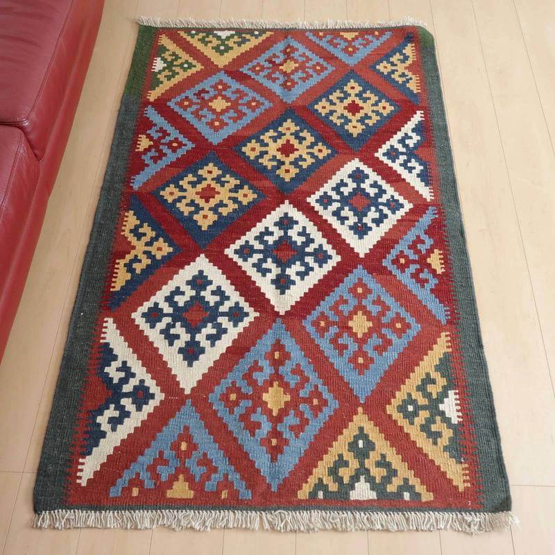 KM-436 165×102cm イラン・シラーズ ウール 平織り 無料 イラン南部シラーズ地方のキリムです。いくつかの色を使用した幾何学柄やギザギザ文様はリズムのある明るい雰囲気。程よく落ち着いた色とウールの風合いが、やさしくインテリアに馴染みます。カシュガイの女性が昔ながらに織り上げたキリムなので、よく締まった丈夫な織り目で、早く仕上げる為、ゆるく粗く織られる商用生産のキリムには無い、誠実さが伝わってくる一枚です。また、平織り（ひらおり）という裏表の無い織り方で両面使えます。カシュガイ族の遊牧のテント生活用の為、丈夫に織られ、洗濯も簡単、床なじみの良い適度な厚さで、普段使いのラグとして大変使いやすいキリムです。 ペルシャ（イラン）産のキリムは、1_飽きのこないデザイン、2_いつの時代もあらゆるインテリアに馴染む、3_モダンで芸術性の高い図柄、として世界各国で、愛用され、それゆえ模倣もされています。図柄の美しさはもちろん、長い歴史に培われてきた製法や織りのテクニックの完成度は、世界最高峰。本物志向の方、違いの分かる方に愛されています。 開封すぐの撮影でシワが見える写真があります。照明の違いで色合いが多少違って見えます。 ※昼白色での撮影