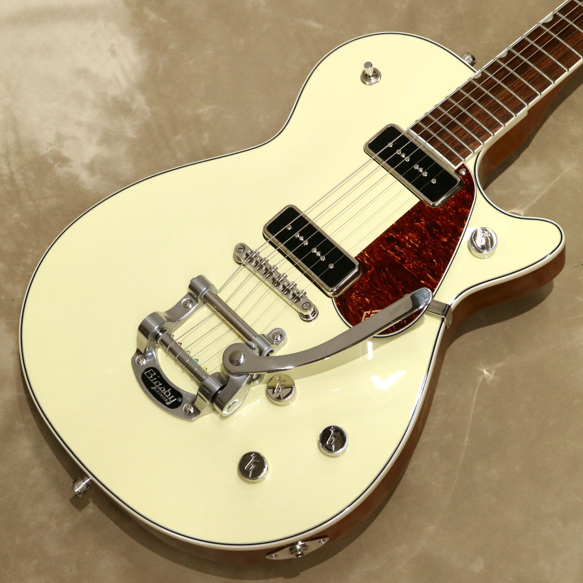 Electromatic Jetは、無駄を一切排除した、完璧でピュア、そしてパワフルなGretschギターです。 大胆でダイナミック、そして明瞭なグレッチ本来のサウンド、洗練されたスタイリング、そして快適な演奏性を備えた、ワンランク上の楽器を求めるプレイヤーに最適な楽器です。 G5210T-P90 Electromatic Jet Two 90 Single-Cut with Bigsbyは、Jetのパワーと機能性をそのままに、お求めやすい驚くべき価格でご提供します。 チェンバードマホガニーボディにメイプルトップを備え、パワフルなクラシックJetサウンドを提供します。 ギグバッグが付属します。 ※主な特徴 ●力強いサウンドと優れた音響バランスを実現するメイプルトップのチェンバードマホガニーボディ ●低めにセッティングされたThin “U”マホガニーネック ●12インチラジアスローレル指板、22本のミディアムジャンボフレットとパーロイドNeo-Classic サムネイルインレイ ●新開発のP-90E Single-Coilピックアップを搭載 ●トレブルブリード回路付きマスターボリューム、マスタートーン、各ピックアップのボリュームコントロール ●Bigsby B50 Vibratoテイルピース ●固定式Adjusto-Maticブリッジ ●ニッケルハードウェア -Specifications- ■Body Material: Chambered Mahogany Body with Arched Maple Top ■Body Shape: Jet ■Body Finish: Gloss ■Neck Material: Mahogany ■Neck Shape: Thin "U" ■Neck Finish: Gloss ■Fingerboard Material: Laurel ■Radius: 12" (305mm) ■Fret: 22Fret/Medium Jumbo ■Position Inlays: Pearloid Big Block ■String Nut: Synthetic Bone ■Nut Wide: 1.6875" (43mm) ■Scale: 24.6" (625mm) ■Pick up Style: P90 / P90 ■Neck Pick up: P-90E Single-Coil ■Bridge Pick up: P-90E Single-Coil ■Controls: Volume 1. (Neck Pickup), Volume 2. (Bridge Pickup), Master Volume, Master Tone ■Pickup Switching: 3-Position Toggle: Position 1. Bridge Pickup, Position 2. Bridge And Neck Pickups, Position 3. Neck Pickup ■Tuning Machines: Die-Cast Sealed ■Bridge: Adjusto-Matic ■Control Knobs: G-Arrow ■Hardware Finish: Nickel ■Switch Tips: Nickel ■Pickguard: Tortoise with Gold Gretsch Logo ■Color: Vintage White ■Case: Gigcase ■Strings: Nickel Plated Steel (.010-.046 Gauges) ■Weight: 約4.05kg