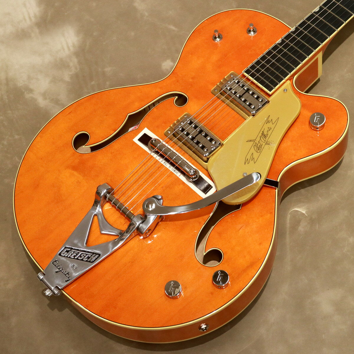 G6120T-59 VS Vintage Select Edition '59 Chet Atkinsは、1959年式のトレッスル・ブレイシングを採用した16インチ幅のメイプル・ホロー・ボディのモデルです。 ヴィンテージ・スタイルのVシェイプ・メイプル・ネックとエボニー・フィンガーボードを組合せ、ゼロフレット仕様の24.6"(625mm)スケールを採用しています。 ハイクォリティーなトーンで人気の高いTV JonesのTV Classicピックアップを搭載しています。 コントロールは、トラディショナルなグレッチ・スタイルで、各ピックアップ・ヴォリュームとマスターヴォリューム、3ウェイ・ピックアップ・セレクター・スイッチと3ウェイ・トーン・セレクターを搭載しています。 さらにグレッチ新開発の“Squeezebox(スクイーズボックス)”ペーパー-イン-オイル・キャパシター(コンデンサー)を採用しています。 Squeezeboxは、シルキーなヴィンテージ・ハイ・エンドのトーンを生み出します。 ピンド・ローズウッド・ベースとBigsbyとの相性も良いロッキング・バー・ブリッジを組み合わせて搭載しています。 コントロール・ノブはニッケル・メッキのGアロー、エイジド・ホワイト・バインディング&ブラック・パーフリング、エイジド・パーロイド・サムネイル・インレイ・ポジションマーカー、ヴィンテージ・スタイルの厚みのあるピックガードを採用するなど、ヴィンテージ・セレクト・エディションの名にふさわしいルックスを備えています。 ハードケースが付属します。 -Specifications- ■Body Top：Laminated Maple ■Body Back：Laminated Maple ■Body Material：Laminated Maple ■Body Shape：Chet Atkins Hollow Body ■Bracing：1959 Style Trestle ■Body Binding：Aged White with B/I Purfling ■Body Finish：Gloss Nitrocellulose Lacquer ■Neck Material：Maple / Neck Shape: Vintage "V" ■Neck Binding：Aged White ■Scale Length：24.6" (625mm) ■Fingerboard Radius：12" (305mm) ■Number of Frets：22 ■Fret Size：Vintage-Style ■String Nut：Bone ■Nut Width：1.6875" (43mm) ■Neck Finish：Gloss Nitrocellulose Lacquer ■Fingerboard：Ebony ■Position Inlays：Aged Pearloid Thumbnails ■Bridge Pickup：TV Jones Classic ■Neck Pickup：TV Jones Classic ■Controls：Volume 1. Neck Pickup，Volume 2. Bridge Pickup，Master Volume，3-Position Tone Switch ■Pickup Switching：3-Position Toggle: Position 1. Bridge Pickup，Position 2. Bridge And Neck Pickups，Position 3. Neck Pickup ■Bridge：Rocking Bar ■Tuning Machines：Grover Sta-Tite Gold ■Pickguard：Gold Plexi with Black Gretsch Logo ■Control Knobs："G" Arrow ■Color：Western Orange Stain ■Strings：Nickel Plated Steel .011-.049 ■Case: Hardcase ■Weight: 約3.45kg