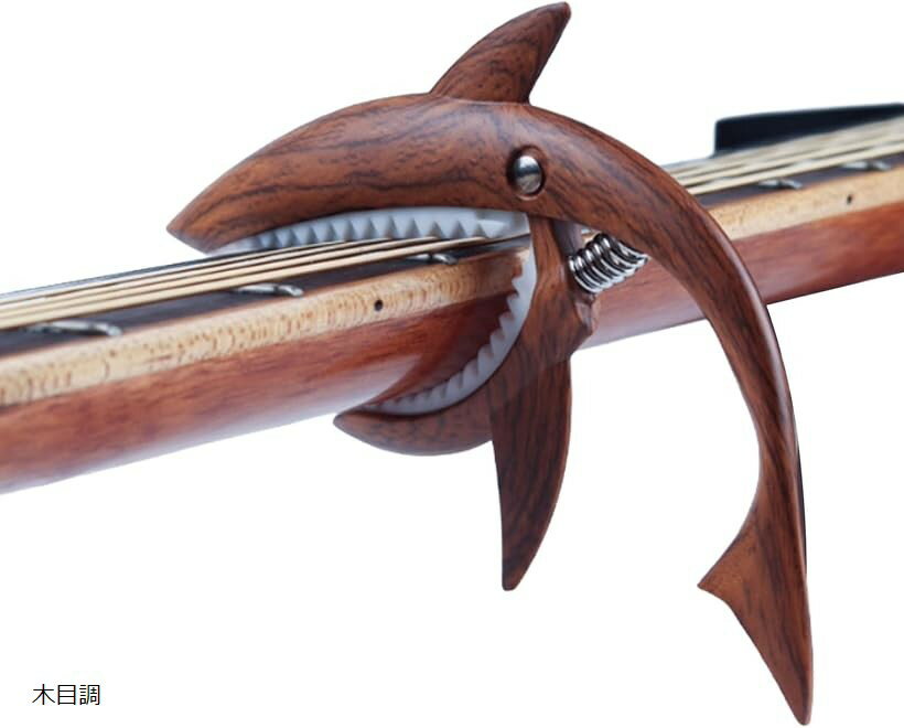 バリエーションコード : 2bug5lryt8商品コード2bug5lryt8商品名ちゃんと固定ギター カポタスト ワンタッチ カポ サメ型 ウクレレ フォーク アコギ エレキ 亜鉛合金 木製ブランドPIENSEカラー木目調サメ型デザインが特徴的なカポタストは、ユニークでかわいい外観がおしゃれなアクセントとなり、練習や演奏の時間をより楽しく彩ります。個性を重視したい方や、ステージやSNSでの発信で人とは違うアイテムを使いたい方にぴったりです。素材には耐久性に優れた亜鉛合金を採用し、錆びにくく長持ちする設計。内側にはシリコンパッドを搭載し、弦や指板をしっかり保護しながらしっかり押さえることができます。繰り返しの使用にも強く、初心者から上級者まで安心して使用できます。ワンタッチで簡単に着脱できる強力スプリングを採用。片手で素早く装着できるため、演奏中のキー変更もスムーズに行えます。ライブや練習を妨げることなく、持ち替えの多い曲や即興演奏でも快適に使える操作性を備えています。アコースティックギター、フォークギター、クラシックギター、エレキギター、さらにウクレレにも対応。幅広い楽器で使用できるため、ジャンルやシーンを問わず活躍します。普段の練習から本番のステージ、音楽教室や動画配信、さらには音楽好きな方へのギフトとしてもおすすめの実用性の高いアイテムです。「仕様」材質：亜鉛合金＋シリコンパッド　サイズ：約14.7x9.5x1.8cm　重量：約113g　対応楽器：アコースティックギター、フォークギター、クラシックギター、エレキギター、ウクレレ　＊モニター環境により色味が異なる場合があります。※ 他ネットショップでも併売しているため、ご注文後に在庫切れとなる場合があります。予めご了承ください。※ 品薄または希少等の理由により、参考価格よりも高い価格で販売されている場合があります。ご注文の際には必ず販売価格をご確認ください。※ 沖縄県、離島または一部地域の場合、別途送料の負担をお願いする場合があります。予めご了承ください。※ お使いのモニタにより写真の色が実際の商品の色と異なる場合や、イメージに差異が生じることがあります。予めご了承ください。※ 商品の詳細（カラー・数量・サイズ 等）については、ページ内の商品説明をご確認のうえ、ご注文ください。※ モバイル版・スマホ版ページでは、お使いの端末によっては一部の情報が表示されないことがあります。すべての記載情報をご確認するには、PC版ページをご覧ください。