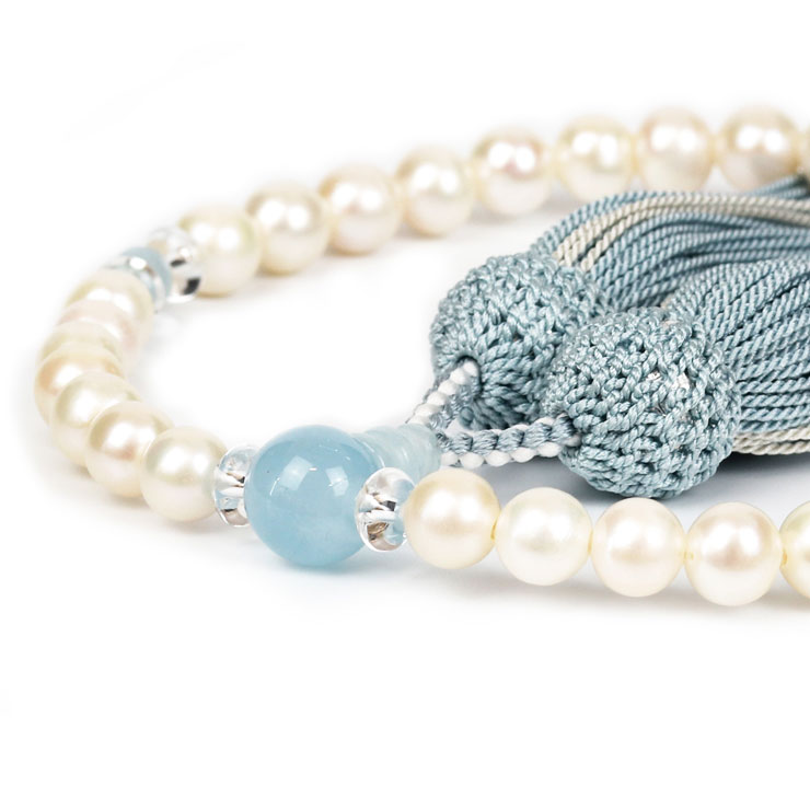 Freshwater Pearl【彩や】 京念珠 淡水真珠 デザイン念珠（女性用） 親玉アクアマリンこちらは主玉を淡水真珠とし、天玉・親玉（アクアマリン）をそろばん型の水晶で挟んだ、デザイン性をもたせた数珠となっております。淡水真珠は、淡水で育つ貝から生まれた真珠で、楕円形などの特徴的な形をしています。真珠は古来から女性美や健康を象徴する宝石として親しまれてきました。また、真珠は涙の象徴とされており、葬儀などの悲しみの席に最もふさわしい宝石とされていますので、数珠の珠の素材としても人気があります。女性の美を象徴する淡水真珠のデザイン念珠親玉：アクアマリン　関係を円満にアクアマリンは持ち主に「幸せ」をもたらしてくれると言われ、「結婚」や「家庭円満」のお守りとして人気のパワーストーンです。見ているだけで癒されるアクアマリンは、心を穏やかにさせてくれるので周りの人に対して優しく穏やかな気持ちで接することができると言われています。夫婦や家族だけでなく友人や職場の方々とも円満な関係を築く「コミュニケーション」のお守りとしてもおすすめです。size彩やの京念珠こちらは略式数珠となります。宗派ごとに定められた本式数珠と異なり、どの宗派でもご利用いただけます。玉数：34玉〜親玉：アクアマリン10mm 主玉：淡水真珠 7mm・本水晶(そろばん型) 6mm天玉：アクアマリン 5mm房色：あさぎ・白銀（頭房）※商品は桐箱に入れてお届けします。 現物に近い色合いで撮影するように心がけておりますが、ご利用の端末、ディスプレイによって実物と若干異なる場合があります。あらかじめご了承ください。