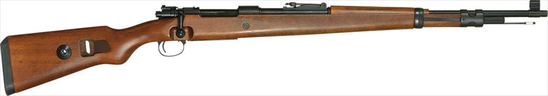 「Kar98k(Karabiner 98 kurz)」は、ドイツのモーゼル社が開発した「Kar98b」をベースに全長を短縮したボルトアクション式小銃です。1935年にドイツ国防軍の制式小銃として採用され、第二次世界大戦を通じてドイツ軍の主力小銃として使用されました。7.92×57mmモーゼル弾を使用し、優れた命中精度と信頼性を備えたKar98kは、歩兵用小銃としてだけでなく狙撃銃としても運用され、W.W.IIドイツ軍を代表する小銃として広く知られています。　「Kar98k AIR」は、このKar98kをモデルとしたエアコッキング式ライフルです。実銃が持つクラシカルなスタイルを忠実に再現し、タナカワークスが得意とする木製ストックと金属製パーツを組み合わせることで、実銃さながらの質感と重量感を実現しました。レシーバーには当時のモーゼル社製を示すメーカーコード「byf」の刻印を再現するとともに、製造年を示す年号刻印など、当時の実銃に見られる特徴的なディテールを盛り込んでいます。内部機構もボルトアクションならではの操作感を楽しめるほか、24発のBB弾を装填可能。可変ホップアップ機構を搭載し、外観のリアリティを損なうことなく実射性能にも配慮しています。　このたび、「Kar98k AIR」がVersion 2にバージョンアップしました。耐久性向上のため、樹脂製だったピストンを削り出し強化アルミ製に変更。スプリングのストレスを受けるスプリングガイドも樹脂製から潤滑コーティングしたスチール製へと改め、スラストベアリングを新たに装備することでスプリングの摩擦抵抗を軽減し、ヨレやブレのない安定した作動を実現しています。さらに、シアラッチをはじめとする細部パーツも強化しており、工場出荷時点でカスタム済みとも言える仕様に仕上がりました。　第二次世界大戦期のドイツ軍制式小銃として知られるKar98kの特徴的なフォルムを、タナカワークスならではの造形と仕上げで再現した、コレクション性と実射性を兼ね備えたエアコッキング・ライフルです。仕様全長：1,103 mm 重量：3,500g 装弾数：24発備考：主要材質 亜鉛ダイカスト+木製ストック※記載されております製品重量等のスペックは生産ロットにより多少の違いが出る場合がございますので、ご了承ください。メーカー名：タナカ種類：エアコッキング形態：トイガンメーカー型番：4537212014212▼商品登録日：2026年10月27日【年齢制限対象商品】ご注文前に必ずお読みください。 ・こちらの商品は青少年育成条例に従い対象外のお客様には一切販売は出来ません。 ・ご注文の前に必ず「年齢制限がある商品の販売条件」をお読みください。