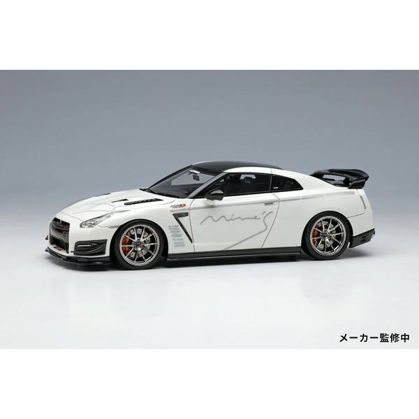 2007年12月に発売が開始されたR35 GT-R。マルチパフォーマンススーパーカーをコンセプトに車体、3.8リッターV6ツインターボエンジン、4WDとトランスアクスルを組み合わせたドライブトレインが専用設計とされていました。イヤーモデル制を敷いて毎年のように改良・進化を行うことが発売当初からアナウンスされ、2022年に製造を終えるまでポルシェ911のGT系とタメを張れる量産型スーパーカーとしてのポジションを維持し続けたのです。2014年にはサーキットユースも視野に入れたエボリューションモデルのNISMOも追加し、こちらも進化を続け、最終型ではついに筑波サーキット2000において、1周1分切りという市販車としては驚異的なラップタイムをマークするに至っています。一方、日産側からはそのパフォーマンスの維持、および保証のために“改造禁止令”ともとれる、発売当初は日産の公認パーツ以外でのドレスアップはおろか、タイヤの銘柄変更でさえも車両保証の対象外になるという措置が採られたと言われています。しかしながらそんな措置をもろともせず、新車当時から数多くのビルダーやメーカーがR35 GT-Rの素性の良さに惹きつけられて改造に着手しています。ROMチューンの雄、神奈川のMine’s(マインズ)もそうしたメーカーのひとつで、R35の発売とほぼ時を同じくした2007年末に行われたREV SPEED誌主催の『第18回 筑波スーパーバトル』に自社のR35を出走させています。翌年には同社お得意のVX-ROMで車載コンピューターをマネージメントするなど種々チューニングを施した車両で筑波サーキット2000で1周1分切りを達成する偉業を成し遂げています。※アクリルベース、クリアーカバー付属スケール：1/43形態：完成品ミニカーメーカー型番：em643商品コード：4570104421668▼商品登録日：2023年02月08日