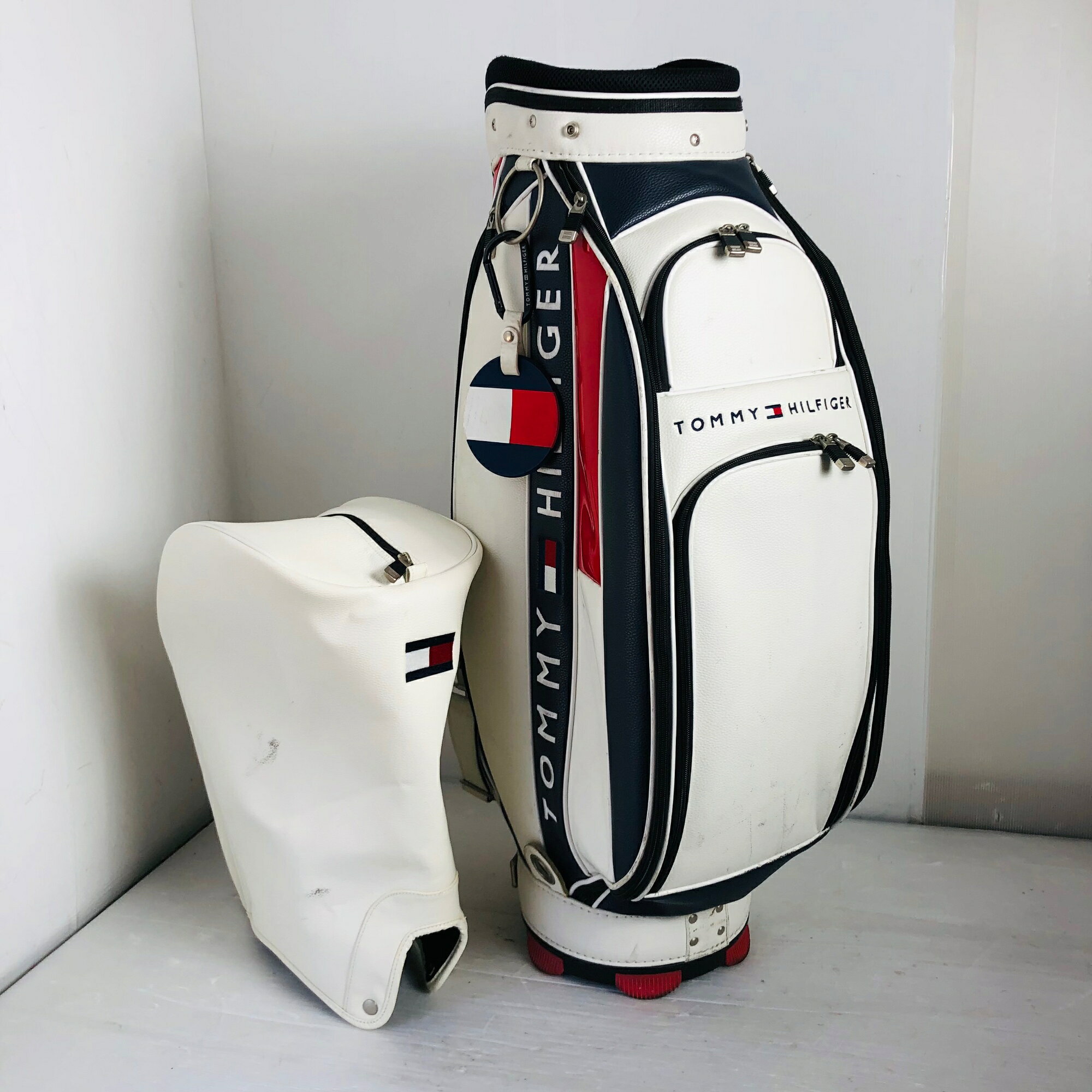 ●商品情報 TOMMY HILFIGER トミー ヒルフィガー 9型 カートタイプ ホワイト ネイビー レッド キャディバッグ ゴルフバッグ ゴルフ 初心者 入門 ※画像にある物が全てです。 ●状態 状態ランク：C ショルダー側のポケットにインク汚れがございます。（写真10枚目） 通常使用に伴う合皮劣化、スレ、傷、汚れはございますが、まだまだお使いいただけます。 ※あくまでUsed品になりますので傷、汚れはございます。画像にてご確認ください。 簡易クリーニング済み S：新品・未使用品 A：非常に状態の良い・美品 B：使用感はあるが目立った傷や汚れのない・良品 C：目につくような傷や汚れがある・一般的な中古品 D：使用するのに問題はないが記載すべき傷、汚れや凹みなどがある ★確認必須事項★ ※商品状態の感じ方には個人差がありますので、“中古品”という事をご理解いただき、神経質な方のご購入はご遠慮ください。 ※基本発送日は月、水、金曜日になります。 祝日等でイレギュラーが発生することもございます。