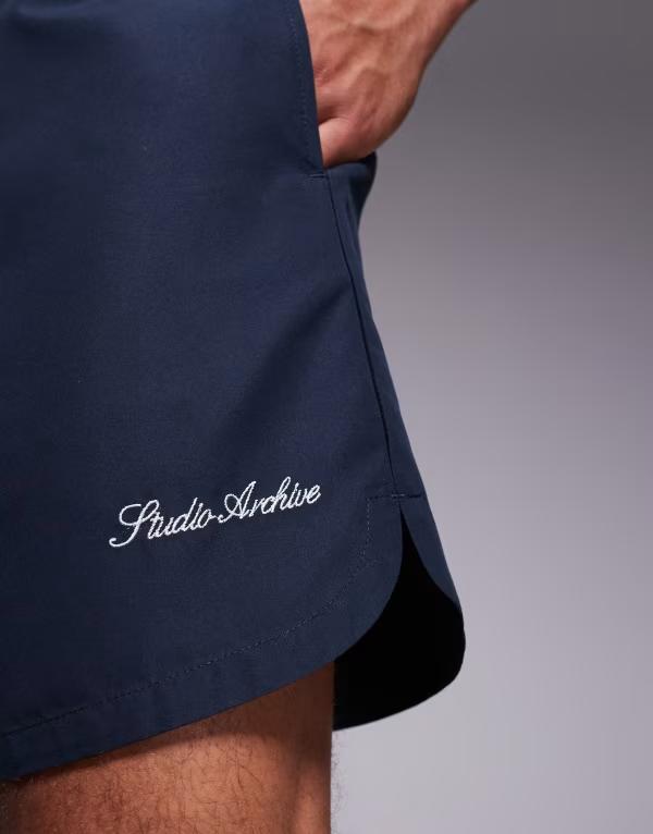 【送料無料】 エイソス メンズ ハーフパンツ・ショーツ 水着 ASOS DESIGN swim shorts in mid length with embroidery in navy NAVY