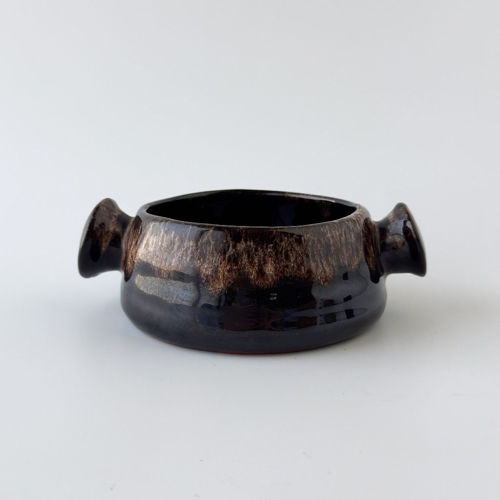 イギリスの陶器メーカー Fosters Pottery (フォスターポタリー)のスープボウルです。 ぽってりとした厚みのあるフォルムに、左右に付いた小さなハンドル。 実用のためのディテールでありながら、その愛嬌あるシルエットがこの器の大きな魅力になっています。 シンプルながらも存在感があり、ヴィンテージならではの落ち着いた佇まいが、食卓や空間に静かな深みを添えてくれます。 スープボウルとしてはもちろん、鍵や小物を入れるトレイとしてもお使いしていただけます。 フォスターポタリー Fosters Pottery 1960年代、イギリス・コーンウォール州で誕生したフォスターポタリーは、蜂の巣のようなハニカム模様と、釉薬がとろりと流れる表情豊かなデザインが魅力の陶器メーカーです。ユーモラスなガーグルジャグなどで親しまれました。現在、当時の工房は閉じられており、生産は行われていないと考えられていますが、英国では会社名義が残っており、主にヴィンテージ品としてスタジオ陶器愛好家やミッドセンチュリー陶器のコレクターの間で人気があります。 装飾・雑貨・食器 食器・キッチン用品 ヴィンテージスタイル 寸法・仕様など **サイズ（単位mm）** - 幅 150 奥行き 120 高さ 50 ＊若干の誤差は御了承下さい。 **主な素材** - 陶器 **特記事項** - スープボウル1点の販売です。 - 写真内のその他の備品は含まれません。 - ユーズド品特有のスレ・小傷がありますが、ご使用上問題ありません。 - 商品コンディションは詳細画像にて必ずご確認お願いします。 - ※輸入の際に食器用の食品衛生検査を行っていない為ディスプレイ用装飾品として販売になります。 コンディションランク ★★★★ 目立った傷や汚れなし コンディションランクについて 経年の使用感、塗装剥げ、傷などはユーズドならではの風合いと考えております。 画像を参考に見た目の雰囲気でご判断頂けると幸いです。 ★★★★★★ 新品、未使用 ★★★★★ 　未使用に近い ★★★★ 　　目立った傷や汚れなし ★★★ 　　　やや傷や汚れあり ★★ 　　　　傷や汚れあり ★ 　　　　　全体的に状態が悪い ＊ 配送料は商品画像内の送料表に基づき、ご注文確定後に別途ご連絡いたします。 すべての商品に関する注意事項 ＊配送指定日はご注文から14日以内、直接お引き取りはご注文から7日以内にお願いいたします。 ＊搬入不可によるキャンセルは受付かねます。ご注文の前に必ず搬入経路、設置場所のサイズ確認をお願い致します。 ＊商品の取り付けや組み立て、配線等はお客様にてお願いします。 ＊商品詳細画像をご覧になれない場合はご連絡ください。画像未確認の場合も返品はお受け致しかねます。 ＊設置に関わる工事費用や新品代替品のご用意等、ご購入代金を超える保証は致しかねます。 ＊商品到着から8日以上が経過した商品の返品・交換、初期不良以外の修理は承りかねます。 ユーズド商品に関する注意事項 ＊店頭や複数モールにて併売しておりますので、ご注文の重複によりキャンセルとさせていただく場合がございます。 ＊不足パーツやメーカーオプション品等についてはお客様にてご確認下さい。 ＊画像掲載枚数に限りがあるため実用に差し支えない部分や、細かい傷などは掲載できない場合があります。 ＊感じ方に個人差がございますが、中古家具における多少の匂いについては予めご了承ください。 ＊前所有者による改造や修理、通常の扱いでは見えない箇所の破損、予想できない経年劣化などにつきましては対応不可となる場合がございます。 ＊ユーズド品は殆どの商品が一点物になります。運送事故や不具合が生じた場合代替品はご用意できません。 ＊購入者様以外のアンティークの特性をご理解頂いていない不特定多数が使用される店舗などでのプロユースは保証対象外となります。 ヴィンテージ、アンティーク商品の取扱について ＊塗装が現代のものに比べ弱く、輪染みや色落ち、色移りの可能性があります。 ＊現代の家具より強度が低く、設置場所や輸送時の温度・湿度によって収縮が生じる場合があります。 ＊オイルやラッカー仕上げが主になりますので、アルコールでの拭き上げはお控えください。 ＊メンテナンスオイルを塗布しての出荷となりますので、水拭き時にオイルが付着し茶色くなります。 新品商品に関する注意事項 ＊お客様が一度ご使用された場合、商品や商品の箱、説明書等を破損・紛失された場合等は返品・交換をお受けできない場合がございます。