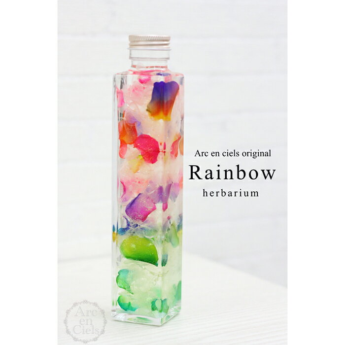 人気のレインボーローズのプリザーブドフラワーのペタル（花びら）を使ったArc　en ciels original ハーバリウム　「Rainbow」他にはないとても綺麗なアイテムが登場。 瓶の中で美しい花びらのグラデーションが目を楽しませてくれることでしょう。 「無限の可能性」という花言葉もとても素敵ですね。 いろんな場面での贈り物としても喜ばれそうなハーバリウムです。 Arc en ciels original のレインボーローズを使用しているため花びらのグラデーションもとても美しい仕上がりになっています。 自社生産のプリザーブドフラワーだからできる特別なアイテムです。 専用のLEDライトスタンドを使えば熱も発しないので安全に楽しむことができます。 場所も取らず香りと光に癒されそう。 使用しているオイルの透過度が高いのでとても美しくご覧になることが出来ます。 ★メッセージカード（無料）をご希望の方は、注文フォームにてメッセージ内容をご入力ください。 ※モニターの発色により実際と異なる場合がございます。 ※パッケージデザイン、ビンの形等変更になる場合がございます。 ※火気の近くや直射日光、高温になる場所には置かないでください。