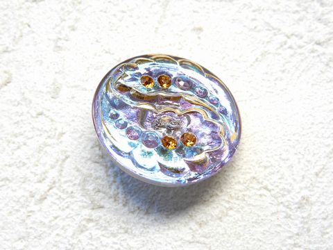商品詳細 素材 チェコ製　ガラス サイズ 直径27mm厚み8mm 商品特徴 ボヘミアングラスの本場チェコ共和国のハンドメイド・ボヘミアグラス・ボタンです。産地のメーカーから直接仕入れている本物の品で、美しさはさすがの本場の逸品です。 中国製や近隣諸国製の安価なものの出現で、現地で生産されているものは徐々に減りつつありますが、味わいのある精緻なガラス細工はさすがに歴史のなせる業物です。 こちらは丸型ボタン。可愛らしいクリスタルの植物型の個性的なデザインが好評です!! 裏にボタンのカン（紐を通すところ）があります。現地では一般的なタイプです。 カラーはクリアーベースにピンク系のオーロラに柄部分にゴールド掛け。ポイントでオレンジの模造ジュエリーが埋め込まれたアンティークな雰囲気が現地でも人気。アクセサリーのポイントTOPにお勧めです。 美しい本場の逸品に是非触れてみて下さい。 ご注意ください ※注 チェコのガラス細工は職人の手作りの為それぞれに若干サイズが異なったり、1粒ごとに色むらができる場合がございます。 予めご了承ください。 ＊画像登録の関係上ご覧のネット環境によっては実物と異なってみえるかもしれませんがご了承お願いします。 ＊この商品は実販売もしております。在庫更新は随時行っておりますが、万が一売り違いの折は、同種の代替の提案かキャンセルして戴く場合もございますので、予めご了承お願いします。 ＊配送について 《メール便の場合》郵便局からのゆうパケット便での配送で、対面受け取りではなく直接郵便受けに配達されます。A4サイズですので同送出来るものなら何点入れても同一価格です。＊＊対象チェコビーズ同時購入ゆうパケット便ご選択で送料無料特典の対象外です!!こちらの商品は個数にカウントされません。ただし同送は可能です!! 《ゆうパケット便の場合》郵便局からの配送で、対面受け取りではなく直接郵便受けに配達されます。宅配便ではないので補償等はございません。予めご了承下さい。 ＊A4サイズですので同送出来るものなら何点入れても同一価格です。 ＊包装は簡易包装となります。 ＊直接配送の場合にプレゼント包装が必要な場合はメールにてお問い合せ下さい（別途費用がかかります）。