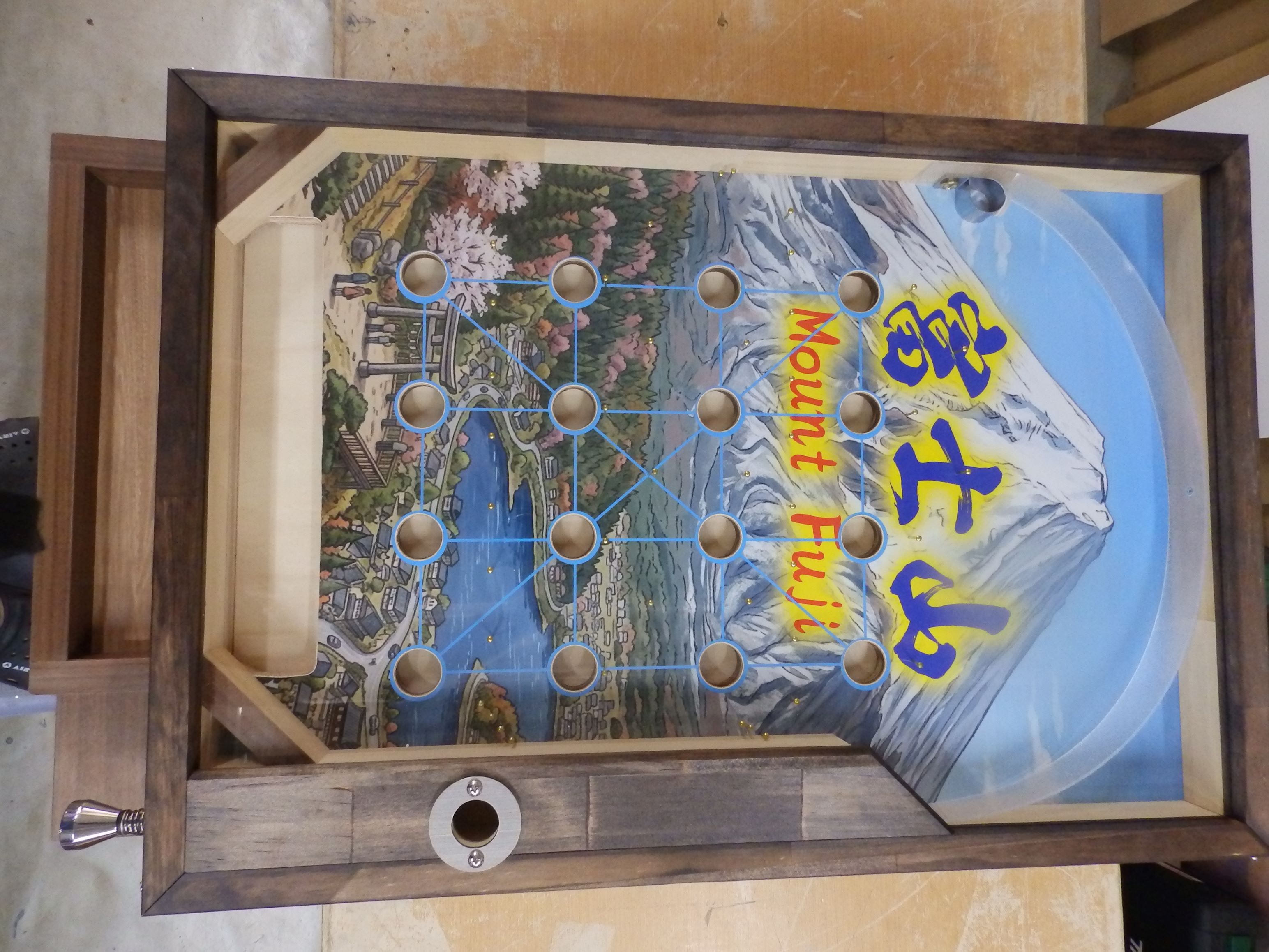 商品情報商品名オリジナル スマートボール （富士山　国内Ver）重量14キロ材質盤面ポリ合板 アンティーク仕様盤面画像インクジェットグロスラミシール本体材質パイン集成材 上部：透明アクリル筐体横面メラミン仕上げの、ウォルナット追柾柄筐体上部枠ウォルナットのオイルステイン仕上げ(アンテーィク感を出すため濃淡を付けています）サイズたて：800　よこ：480　高さ：220ボールガラス ※ホワイトマーブル25個　予備の釘10本運用方法手動式リターン 傾斜調整アジヤスター付色についてモニターの発色の具合によって、実際の物と色が異なる場合が御座いますはじめに本製品は、一品一品手作りで製作しており、特にオイルステイン仕上げ（上部枠の塗装）などは、一品ずつ風合いが異なりますのでご了承下さい、基本的な作りは変わりません。屋外での使用は直射日光をさけて下さい、メラミン化粧版がはがれる原因となります。納期14日〜21日営業日以内に発送予定ですが、繁忙期にはさらに2〜4週間程度頂く場合がございます、ご了承ください。詳しくはお買い上げ前にご確認いただけましたら幸いです。スマートボール 　富士山　国内Ver　 お祭り イベント レクリエーション イベント用品 縁日用品 サムサフイ samsaffy イベント用品 縁日用品 お祭り 夏祭り 秋祭り 花火大会 レクリエーション 　スマートボール　温浴施設イベント イベントツール ラッキーボール 販促イベント 　富士山イベント こんな場面におすすめ 夏に開催される花火大会や夏祭りのほか、たくさんの人でにぎわう地域の縁日やイベント、販促会、展示会、学校関連のバザーや学園祭、子供会、集客イベントなど、さまざまなイベントや催しが開催されます。ほかにも、スマートボールが大活躍するシーンは、飲食店のキャンペーン、温泉施設やリゾート施設、ガソリンスタンド、行楽地、駄菓子店、飲食店の集客イベント、イベント用品 縁日用品 ディスプレイ用品として、それに福祉用のレクリエーションなど、ありとあらゆる目的を持つ施設やさまざまなシーンで活用されています。 昭和の懐かしい商品をお探しなら ワイワイ楽しく過ごすなら お子さまや大人まで楽しんでもらえるなら 縁日やイベントに イベントの企画を担当することになったとき 町内会主催のお祭りも家族や友だちとワイワイ 昔遊びには色々な種類がありますが、何世代にもわたり遊び継がれている理由は一体どのような魅力が関係しているのでしょうか。【すぐ面白い】が魅力と考えます。お祭りや縁日などで遊ぶことができる定番の昔遊びとして、昔も今も変わらず高い人気を維持しているのが、こちらでご紹介する「スマートボール」です。ピンボールと似た遊び方ですが、盤面が横向きになっているのが特徴で、横物と呼ばれます、遊び方は、レバーを操作して玉を盤面に打ち出し、盤面上にある穴に入れるというもの縦・横・斜めのライン（4個1列）を揃えた数がプレイヤーの得点となります。比較的簡単に遊べるゲームなので、三世代子供でも大人数でも楽しく遊べます。縁日など是非スマートボールに挑戦してみてください。 1