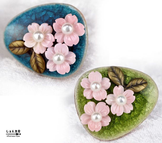 他のオススメも御座います。(*´＿｀*)青色が綺麗な焼きものに天然色のピンク色が大変美しい 桜の花（極上天然コンク貝）をあしらった素敵な帯留めをお作り致しました。(*´＿｀*) 藍色・若草色と綺麗な桜色のコントラストがとても美しい仕上がりとなりました。 桜の花芯には照りの良い本真珠を添え、更に素敵に。o○ 　 　 マロン型の帯留めは品の良い小振りサイズ28×24ミリでございます。 上下どちらでもご使用頂けます。 ☆西インド諸島ドミニカ共和国のカリブ海に生息しているコンク貝。 コンクパールの母貝として有名なクイーンコンク貝の綺麗なピンク色部分だけを使用し 美しくカービンされた極上天然コンクシェルを使用しております。 商品詳細 材質 【天然石】 ・天然コンクシェル ・上質淡水真珠 【パーツ】 ・合金（金具） サイズ 【全長】 ・28×24ミリ程 【帯締め通し】 ・内径：10×6ミリ程 その他