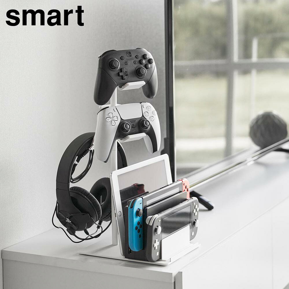 商品名称 仕切りが動くゲーム機&コントローラースタンド スマート 商品スペック 商品サイズ W15×D21×H40.8cm 置き台回転時最大：W16.5×D24.8cm 重量 915g 耐荷重 置き台1つあたり：500g(静止荷重) 品質表示 パイプ×2・台座：スチール(粉体塗装) コントローラー置き台×3：ABS樹脂 仕切り板：ポリプロピレン ストッパー×6・クッション：シリコーンゴム 原産国 中国仕切りが動くゲーム機&コントローラースタンド スマート 小型ゲーム機やタブレット ゲームコントローラーなどを まとめて収納できるスタンド 小型ゲーム機やゲームコントローラーをまとめてスリムに収納できるスタンドです。 仕切りをスライドして収納幅が変えられ、様々な小型ゲーム機、厚みのある充電ドックや薄型のタブレットやスマホなどを立てて置けます。 コントローラーやヘッドセットを収納できる置き台は3つ。収納するものに合わせて高さと向きを調節して配置できます。また、置台にはケーブルが通るスリットがあり、充電ケーブルをホールドできるので置いたまま充電ができ、充電しない時もケーブルを引っ掛けておけるので便利です。 たくさん収納しても縦にスッキリ整頓できるから、TV横やデスクまわりなどの限られたスペースにおすすめです。