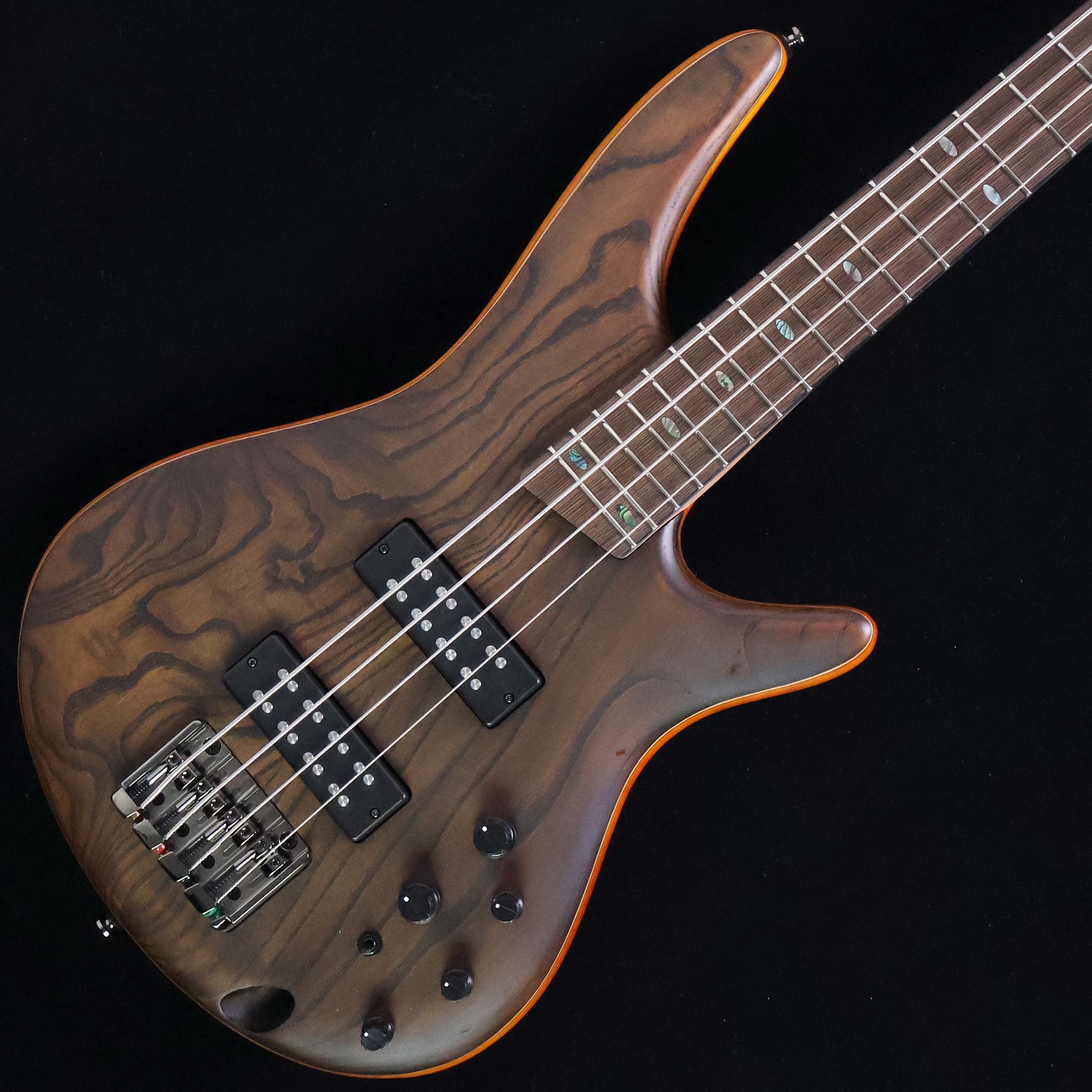 軽量&薄型ボディのSRシリーズ　島村楽器×Ibanez コラボレーションモデル【特徴】ボディには贅沢にアッシュ・トップ、ウォルナット、ニャトーを重ねた積層構造を採用。PrestigeやPremiumといった上位モデルのようなウッディな風格を漂わせ、豊かな中低音にアッシュ特有のパンチ力を加えた実戦的で抜けの良いサウンドを誇ります。カタログモデルにはない「EQ ON/OFF（アクティブ/パッシブ）スイッチ」を特別に搭載。これにより、万が一の電池切れの際でもパッシブモードに切り替えてそのまま演奏が可能です。ピックアップには重厚でパワフルなサウンドが特徴の「PowerSpan Dual Coil」を搭載。スリムで演奏性に定評があるSR独自のネック形状による抜群の弾きやすさも魅力です。【杢目マニア花井のイチオシポイント！】上位モデルに迫る風格の積層ボディを採用した当社限定モデル。スリムなボディとSR独自の極細ネックによって抜群の演奏性を実現しています。アッシュ特有の芯の太い実戦的サウンドですが、パッシブに切り替えれば温かみあるトーンも楽しめます。EQのON/OFFスイッチにより、バッテリー切れでも音が出せる機能は急な電池切れといったトラブルに強く安心感が違います。初心者の方から2本目をお探しの方まで、自信を持っておすすめできる使い勝手に優れた一本です。この商品についての詳しいお問い合わせは TEL：0570-020-025 または「お問い合わせフォーム」よりお願いします。 【花井's Profile】長野県松本市出身。三度のメシより杢（もく）が好き、自他ともに認める杢目マニア。14年間勤務していた松本店では「ギター生産量日本一」の環境を活かし地元のメーカーや工房とコラボレーションしたショップオーダーモデルなどを多数企画。ギターの製作現場にて数々の職人とミーティングを重ね木材の知識やカスタムオーダーのノウハウを蓄積。これまで培った知識と経験を活かし、彼自身がセレクト〜撮影までおこなったギターをオンラインストアに掲載中。その魅力を全国のギターファンに伝えている。【詳細情報】BODY TOP ： AshBODY ： Walnut / NyatohNECK ： Jatoba/Walnut（5pc）FRETBOARD ： Bound Panga Panga w/Avalon SR Special inlayFRET ： MediumBRIDGE ： Accu-cast B120 bridge（19mm String Spacing）NECK PICKUP ： Ibanez PowerSpan Dual CoilBRIDGE PICKUP ： Ibanez PowerSpan Dual CoilEQUALIZER ： Ibanez Custom Electronics 3-band EQ（w/EQ ON-OFF switch）STRING GAUGE ： .045、.065、.085、.105WEIGHT ： 3.62kgJANコード：4549763355959【mtmt_hni】