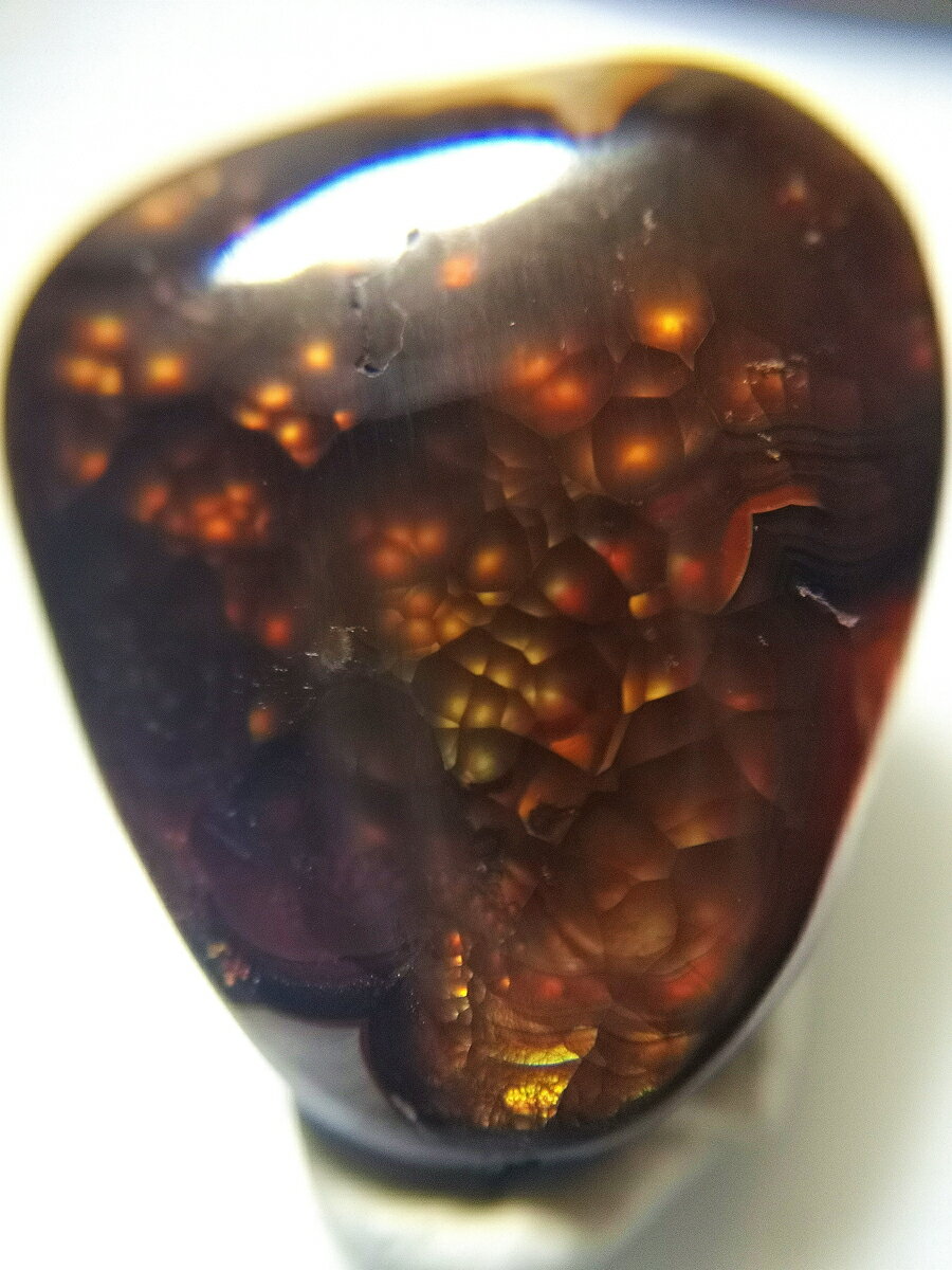 商品名『メキシコ　アグアスカリエンテス産　ファイヤーアゲート 19.3 ct』産地メキシコ（Mexico)　アグアスカリエンテス（Aguascalientes)　内容量約 3.86 g 19.3 ct （多少前後あります）寸法約 22 × 20 × 6 mm 　（前後）商 品 紹 介☆メキシコ北中部のアグアスカリエンテスで現地買い付けをしました。★遊色効果（イリデッセンス効果）のあるファイヤーアゲートの入荷です。石の内部に泡のように形成された粒が、光輝き、ゆれ動く不思議な様子はまるで生きているかのようです。☆まるで宇宙空間のような細やかなバブルの集合体。オレンジのみのシンプルな遊色ですが、石全体に現れる様は圧巻です。落ち着いた茶色の地色も宇宙っぽさを増しています。★そのまま眺めるもよし、ケースに入れてお守り代わりに持ち運ぶのもよし、アクセサリーのパーツにするもよし、瞑想に使ったり、お守りにしたり、プレゼントにも最適です。※実物の色に近づけるように撮影していますが、商品と写真とでは違った印象を受ける場合がありますのでご了承ください。※サイズは良くお確かめください。 石 言 葉 別名：炎瑪瑙対応チャクラ：第四チャクラ、心臓モース硬度：6.5-7 ・積極性を高める・エネルギーを活性化する・マイナスエネルギーの浄化・グラウディング・ストレス解消・燃えるような情熱を後押しする。&#12316;自然が生み出す驚異の游色&#12316;メキシカンファイヤーアゲート 「情熱と積極性」の石、ファイヤーアゲートは、アゲートに属する鉱物の一種です。 アゲートはカルセドニーの変種にあたりますが、カルセドニーの中でも模様がくっきりと見られるものをアゲート、その中でも燃えるような炎の模様を特徴とする石が「ファイヤーアゲート」と分類されています。 ここまではよく知られている話ですが、ファイヤーアゲートにも実は2種類ある、ということはあまり知られていません。よくビーズなどで出回っている、波打つような炎そのものに見えるファイヤーアゲートは、実際は赤またはオレンジの単なる「アゲート」の場合も多く、着色加工により炎の模様を再現したものも多く存在します、流通量も多く、比較的安価な場合が多いです。 一方、今回ドラゴンクリスタルが仕入れたのは、メキシコ北中部とアメリカ南西部のみで産出が確認されている遊色効果（イリデッセンス効果）のあるファイヤーアゲートです。 カルセドニーの内部にインクルージョンとなって取り込まれたリモナイト(褐鉄鉱)が光を受ける事で、「虹色の炎」の遊色効果が見られます。このタイプが本来の「ファイアーアゲート」と呼ばれるもので、希少価値が高い鉱物として扱われます。 石の内部に泡のように形成された粒が、光輝き、ゆれ動く不思議な様子はまるで生き物のように感じます。 通常は茶色の下地に緑やオレンジの遊色ですが、レアカラーでブルー、紫、ピンクが浮き出る事があり、これらはさらに希少価値が高くなります。 ボコボコと凹凸がある部分に遊色が出ていますので、原石を平面に削っただけでは良い色が出るとは限りません。 　そのためリューターなどを使い発色の良い部分を探しながら立体的に削っていかねばならず、 研磨に関しても高い技術が要求される鉱物になります。 中国やアメリカや日本の宝石店では驚くほど高値で取引されていますが、 当店ではスぺシャルなピースに出会うため毎年メキシコ中央部にあるAguascalientes（アグアスカリエンテス）周辺にて現地直接買い付けをしており、そのメリットを活かしお求めやすい金額で出品させて頂いております。 是非この機会にコレクションに加えてはいかがでしょうか？ ※商品写真と商品現物の色味に若干の差がある場合がございます。