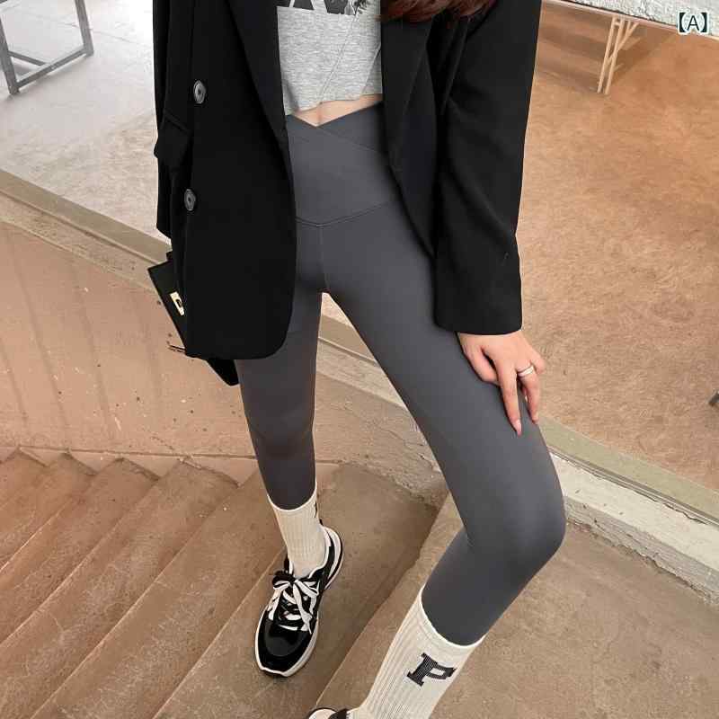 黒い サメの ズボンの 女性は ベルベットの ヨガの やせた 脚を 着て 腹を 上げて 腰の v 字を 交差 さ せた 腰の バービーの レギンスを 持って いる