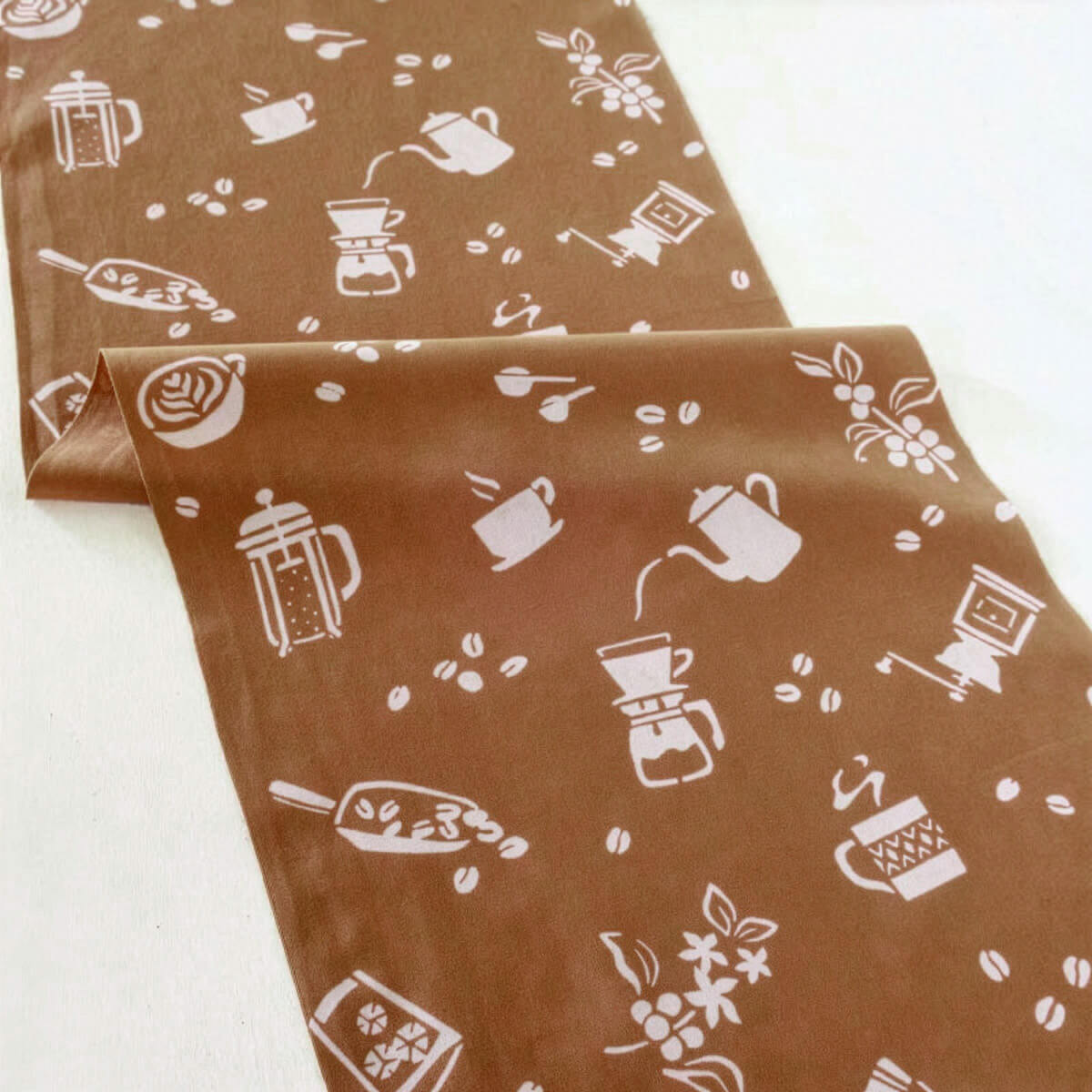 Size：約W35×H90cm 素材：綿100％(てぬぐい生地) 染色方法：型染め 作家：amiu(山梨県) ※一つ一つ手作業のため、色ムラや滲み、かすれ、版ズレなどがございます。 　手染めならではの独特の風合いをお楽しみください。 ※両端は切り放しになりますので若干のほつれがあり、 　端が不揃いな場合があります。 　最初のうちは両端からほつれますが、何度か洗ううちに落ち着きます。 【型染めについて】 和紙に柄を彫り抜いて作った型を使用した染色方法です。 浸染という方法で染液に浸けて染めることから、裏は1色に染まっています。 糊を置いたところが白く残り柄が浮かび上がります。 表の白地にもうっすら色が透けて見えるため真っ白ではありません。 【染料について】 水や日差しに強い染料です。 ※完全に色落ちしないわけではありません。 お湯、漂白の強い洗剤での洗濯、経年変化などによる色落ちは多少ございます。 amiu 手染め 手ぬぐい　商品一覧はこちら日常に伝統とアートを、 『amiu』の型染め手ぬぐい。 日本の伝統的染色技法「型染め」で作られた『amiu』の手ぬぐいです。 染色家のTOSHIEさんがデザインから型作り、染色、商品化に至るまで、 すべての工程を一人でていねいに手がけています。 伝統的な技法を活かしながらも、和の枠にとらわれないモダンカジュアルなデザイン。 手染めならではの柔らかい線や、かすれ、版ズレなど、デジタル印刷では表現できない独特の風合があり、 素朴で温かみのある雰囲気を楽しめます。 もちろん、手拭きとしての用途だけでなく、首や頭に巻いてファッションアイテムとして楽しんだり、 お弁当包みやテーブルクロスとして使ったり、タペストリーのように壁に飾るのも素敵です。 柔らかな手ぬぐい生地は使い心地が良く、シンプルな柄と落ち着いた色合いで、 老若男女問わずおすすめ。 さらに、おしゃれなパッケージ入りなので、ギフトにもぴったりです。 ～ Coffee #1 モカ ～ コーヒーを入れる時に立ち上る湯気と香り、豆を挽く感触、カップを選ぶ楽しみ、 コーヒは飲んでいる時だけでなく、全てのプロセスで幸せな時間を与えてくれます。 そんなコーヒーの楽しさを、さまざまなモチーフで表現しました。 型染めについて 型染めは、模様を掘り抜いた型紙を使って染める方法で、大きく3つの種類があります。 1つめは、ステンシルのように型の抜けている部分に直接顔料を摺り込む方法です。 2つめは、糊に染料を混ぜて色糊を作り、型付けして蒸す方法で、型を抜いた部分に色がつきます。 3つめは、型紙を使って防染糊を置き、その後染料で染める方法です。 amiuさんの型染めは、この3つめの技法を使っており、和紙に柄を彫り抜いた型を用いて染色を行っています。 浸染という技法では、生地を染液に浸して染めるため、裏面は一色に染まります。 また、糊を置いた部分は白く残り、柄が浮かび上がります。 表の白地にもうっすら色が透けるため、真っ白ではなくやさしい風合いが生まれます。 さらに、表現によって異なる技法を組み合わせることもあるそう。 デザインから染色まで、すべてが手作業。 ●デザイン 模様の元になる絵柄を手描きでデザイン。 (手描きならではの揺らぎや温もりを大切にしています) ↓ ●型作り 型紙にデザインを写し、カッターで丁寧に彫り抜きます。 （切り絵のように彫っていく、根気のいる工程です） ↓ 型が壊れないよう、細かいネットを貼って補強します（紗張り） ↓ ●糊置き 布の上に型をのせ、ヘラで防染糊を置いていきます。 （この糊を置いた部分が白く残り、柄になります） ↓ ●染め 植物などから染料を煮出し、刷毛で何度も引き染め （染めて → 乾かして → 媒染して → また染めて……と繰り返す地道な工程) ↓ ●糊を落とす 最後に水で糊を落とすと、ようやく模様が現れます。 （この瞬間が一番の楽しみでもあり緊張の瞬間） ↓ ●色止め 色が落ちないよう、草木染めや染料に合わせて色止めをして完成 ＋α：染めの前準備 実は染める前にも大切な下処理があります。 生地の汚れや糊を落とす「精錬」を行うことで、染料がより均一に浸透しやすくなります。 草木染めの場合は、豆乳を染み込ませる「豆汁（豆乳）引き」で、発色を鮮やかにし、色の定着を助けます。 自然の色合いと手仕事の丁寧さが調和した、 型染めならではの奥行きある表情をお楽しみください。 てぬぐいを長くお使いいただくために。 水や日差しに強い染料ですが、完全に色落ちしないわけではありません。 漂白剤や強い洗剤は避け、中性洗剤を使うことで色落ちを防ぎます。(手洗いがおすすめ) 洗った後はシワを伸ばして陰干しをおすすめします。 最初のうちは両端からほつれますが、何度か洗ううちに落ち着き、 端から1cm程で自然に止まるのがすごいところ。 ほつれたら長く出た糸だけをはさみで切ってお使いください。 【型染めamiu （日本）】 日本の伝統的染色方法「型染め」でオリジナルの柄を制作。 自然物をイマジネーションの発端に、目に見える姿と見えない何かを意識し、独自の柄を考案。 日本の伝統技術を尊重しつつ、和にこだわらない新しい表現を模索しています。 日常に伝統とアートを取り入れられるような作品づくりを目指しています。 型染め/染色作家 TOSHIE 自然豊かな環境の中で生まれ育ち、幼少期は絵を描くことに夢中でした。 中学時代、美術の先生が油絵画家だったことが縁で、美術専門学科のある高校へ進学。 そこから油絵を描き始め、武蔵野美術大学で油絵と銅版画の作品を制作。 アメリカのThe Art Institute of Portlandでデザインを学び、帰国後デザイン会社に入社し、その後独立。 2012年から染色を始め、2015年にamiuを立ち上げ、草木染めを学びながら、デザイナー・染色家として活動中。 amiu 手染め 手ぬぐい　商品一覧はこちら