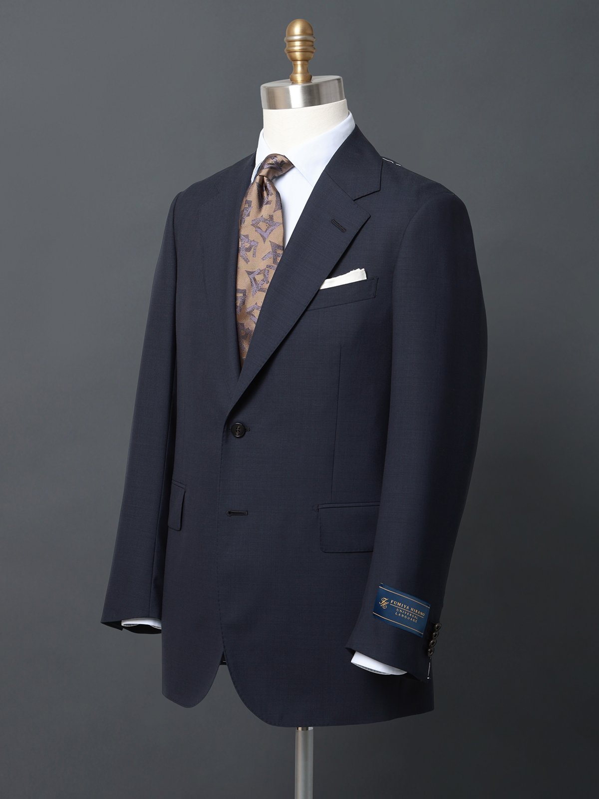 SUIT SQUARE（スーツ スクエア）FUMIYA HIRANO ジャケット SUPER100'sウールトロピカル国内外で高い人気を誇るテーラー、平野史也氏監修のテーラードジャケット。本場英国仕込みの立体美と、日本人体型へのフィット感を両立させた平野氏ならではのカッティングを既製服で再現。平野氏監修企画では初となるセットアップジャケットは、滑らかさと柔らかさのある生地をセレクト。日本人体型に合わせた英国仕込みのパターンに落とし込むことで、高級感と信頼感を備えたモダンブリティッシュな1着に仕上がっています。【モデル】　FUMIYAHIRANO×UNIVERSALLANGUAGE（FH01）日本人体型に合わせつつ、本場英国仕込みの構築的な肩回りや長めの着丈、高いウエスト位置からのシェイプが特徴的なモデル。身体に吸い付くような極上のフィット感を実現しています。【生地】高級原料であるSUPER100'sウールを使用した、滑らかでクリアな風合いのトロピカル組織。適度なハリ感と落ち感を併せ持ち、美しいドレープを描くファブリック。平織りならではの通気性の良さや軽さが春夏シーズンに最適な素材です。《英国仕込みのこだわりのディテール》・袖山を自然に盛り上げたロープドショルダーは英国の雰囲気たっぷり・低めのゴージ位置から広がるエレガントな広幅ラペル・英国仕立てに見られる25ミリ幅のフラワーホール・ジャケット腰ポケットのフラップをやや広めに変更・長めの着丈と深めに入れたサイドベンツで、後ろ姿も華麗に《一格上の着用感を実現する縫製と仕様》・首に吸い付く上襟ののぼりにより、ジャケットの重心を支え心地よい着用感に・丁寧なアイロンワークによるクセ取りで、立体的な胸元とウエストシェイプの優雅な対比が実現・コンパクトなアームホールはフィット感ある着心地ながら、手縫いに近い快適さ・前身頃裾まで入った総毛芯仕立てで、ハイクオリティなスーツがいつまでも美しいシルエットにビジネス　ビジネスカジュアル　オフィスカジュアル　テーラード＊セット着用可（パンツは別売りとなります。）パンツ：7661867【仕様】シングルブレスト／2つボタン／背抜き仕立て／本切羽／サイドベンツ【モデル】FH01※モデルにより仕上がりサイズが異なります。下記のサイズ詳細を必ずご確認下さい。【洗濯表示】ドライオンリー型番：3661860-MB-19-A4 RR3205【採寸】【(165cm-6DROP)A4】着丈71.0cm　バスト106.5cm　ウエスト89.0cm　肩幅45.3cm　袖丈58.0cm【(170cm-6DROP)A5】着丈73.0cm　バスト108.5cm　ウエスト91.0cm　肩幅46.0cm　袖丈59.5cm【(175cm-6DROP)A6】着丈75.0cm　バスト110.5cm　ウエスト93.0cm　肩幅46.7cm　袖丈61.0cm【(180cm-6DROP)A7】着丈77.0cm　バスト112.5cm　ウエスト95.0cm　肩幅47.4cm　袖丈62.5cm【(165cm-4DROP)AB4】着丈71.0cm　バスト109.5cm　ウエスト94.0cm　肩幅46.3cm　袖丈58.0cm【(170cm-4DROP)AB5】着丈73.0cm　バスト111.5cm　ウエスト96.0cm　肩幅47.0cm　袖丈59.5cm【(175cm-4DROP)AB6】着丈75.0cm　バスト113.5cm　ウエスト98.0cm　肩幅47.7cm　袖丈61.0cm【(180cm-4DROP)AB7】着丈77.0cm　バスト115.5cm　ウエスト100.0cm　肩幅48.4cm　袖丈62.5cm※商品の仕上がりサイズ（出来上がり寸法）は上記のサイズ表をご覧下さい。※お届けする商品の下げ札・タグに記載の数値は目安としてのヌードサイズ（体の寸法）のため上記表示と異なる場合がありますが、誤表記ではございません。※同サイズまたは同一商品でも、生産の過程で1.0cmー2.0cm程度の個体差や着用感の違いが生じる場合がございます。※カラー名は管理用の表記となります。実際の商品の色味は商品画像をご確認ください。※商品画像はできる限り実際の色に近づけて掲載しておりますが、パソコン環境により色味に誤差が生じる場合がございます。予めご了承下さいませ。商品のサイズについて【商品詳細】ミャンマー素材：ウール100％　裏地：（胴）ポリエステル52％／レーヨン48％　（袖）キュプラ100％サイズ：165-drop6、165-drop4、170-drop6、170-drop4、175-drop6、175-drop4、180-drop6、180-drop4※画面上と実物では多少色具合が異なって見える場合もございます。ご了承ください。商品のカラーについてSUIT SQUARE（スーツ スクエア）FUMIYA HIRANO ジャケット SUPER100'sウールトロピカル国内外で高い人気を誇るテーラー、平野史也氏監修のテーラードジャケット。本場英国仕込みの立体美と、日本人体型へのフィット感を両立させた平野氏ならではのカッティングを既製服で再現。平野氏監修企画では初となるセットアップジャケットは、滑らかさと柔らかさのある生地をセレクト。日本人体型に合わせた英国仕込みのパターンに落とし込むことで、高級感と信頼感を備えたモダンブリティッシュな1着に仕上がっています。【モデル】　FUMIYAHIRANO×UNIVERSALLANGUAGE（FH01）日本人体型に合わせつつ、本場英国仕込みの構築的な肩回りや長めの着丈、高いウエスト位置からのシェイプが特徴的なモデル。身体に吸い付くような極上のフィット感を実現しています。【生地】高級原料であるSUPER100'sウールを使用した、滑らかでクリアな風合いのトロピカル組織。適度なハリ感と落ち感を併せ持ち、美しいドレープを描くファブリック。平織りならではの通気性の良さや軽さが春夏シーズンに最適な素材です。《英国仕込みのこだわりのディテール》・袖山を自然に盛り上げたロープドショルダーは英国の雰囲気たっぷり・低めのゴージ位置から広がるエレガントな広幅ラペル・英国仕立てに見られる25ミリ幅のフラワーホール・ジャケット腰ポケットのフラップをやや広めに変更・長めの着丈と深めに入れたサイドベンツで、後ろ姿も華麗に《一格上の着用感を実現する縫製と仕様》・首に吸い付く上襟ののぼりにより、ジャケットの重心を支え心地よい着用感に・丁寧なアイロンワークによるクセ取りで、立体的な胸元とウエストシェイプの優雅な対比が実現・コンパクトなアームホールはフィット感ある着心地ながら、手縫いに近い快適さ・前身頃裾まで入った総毛芯仕立てで、ハイクオリティなスーツがいつまでも美しいシルエットにビジネス　ビジネスカジュアル　オフィスカジュアル　テーラード＊セット着用可（パンツは別売りとなります。）パンツ：7661867【仕様】シングルブレスト／2つボタン／背抜き仕立て／本切羽／サイドベンツ【モデル】FH01※モデルにより仕上がりサイズが異なります。下記のサイズ詳細を必ずご確認下さい。【洗濯表示】ドライオンリー型番：3661860-MB-19-A4 RR3205【採寸】【(165cm-6DROP)A4】着丈71.0cm　バスト106.5cm　ウエスト89.0cm　肩幅45.3cm　袖丈58.0cm【(170cm-6DROP)A5】着丈73.0cm　バスト108.5cm　ウエスト91.0cm　肩幅46.0cm　袖丈59.5cm【(175cm-6DROP)A6】着丈75.0cm　バスト110.5cm　ウエスト93.0cm　肩幅46.7cm　袖丈61.0cm【(180cm-6DROP)A7】着丈77.0cm　バスト112.5cm　ウエスト95.0cm　肩幅47.4cm　袖丈62.5cm【(165cm-4DROP)AB4】着丈71.0cm　バスト109.5cm　ウエスト94.0cm　肩幅46.3cm　袖丈58.0cm【(170cm-4DROP)AB5】着丈73.0cm　バスト111.5cm　ウエスト96.0cm　肩幅47.0cm　袖丈59.5cm【(175cm-4DROP)AB6】着丈75.0cm　バスト113.5cm　ウエスト98.0cm　肩幅47.7cm　袖丈61.0cm【(180cm-4DROP)AB7】着丈77.0cm　バスト115.5cm　ウエスト100.0cm　肩幅48.4cm　袖丈62.5cm※商品の仕上がりサイズ（出来上がり寸法）は上記のサイズ表をご覧下さい。※お届けする商品の下げ札・タグに記載の数値は目安としてのヌードサイズ（体の寸法）のため上記表示と異なる場合がありますが、誤表記ではございません。※同サイズまたは同一商品でも、生産の過程で1.0cmー2.0cm程度の個体差や着用感の違いが生じる場合がございます。※カラー名は管理用の表記となります。実際の商品の色味は商品画像をご確認ください。※商品画像はできる限り実際の色に近づけて掲載しておりますが、パソコン環境により色味に誤差が生じる場合がございます。予めご了承下さいませ。商品のサイズについて【商品詳細】ミャンマー素材：ウール100％　裏地：（胴）ポリエステル52％／レーヨン48％　（袖）キュプラ100％サイズ：165-drop6、165-drop4、170-drop6、170-drop4、175-drop6、175-drop4、180-drop6、180-drop4※画面上と実物では多少色具合が異なって見える場合もございます。ご了承ください。商品のカラーについて