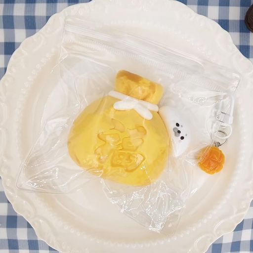 【ぷにぷに水感触感】:みずみずしく柔らかな触り心地を楽しめる水感スクイーズです。指で押したり、手のひらでぎゅっと握ったりすると、むにゅっと形が変わるぷにぷに・もちもち触感。手を離すとゆっくり形が戻る低反発タイプで、何度も触りたくなる心地よさです。仕事、勉強、家事の合間に使えるストレス解消グッズやストレス発散グッズとして活躍します。 【福袋xアザラシの縁起デザイン】:鮮やかな黄色い福袋に、白くて丸いアザラシが抱きついた遊び心のあるデザイン。袋の中央には縁起のよい文字が立体的に表現され、見ているだけでも気分が明るくなるかわいい動物スクイーズです。一般的な食べ物スクイーズとは違う個性的な見た目で、机や棚に飾る癒し雑貨、写真を撮りたくなるSNS映えアイテムとしても楽しめます。 【キーホルダー付きで携帯便利】:キーホルダー付きなので、バッグやリュック、ポーチなどに取り付けて持ち運べます。外出先でも気になったときに取り出して握れる、便利なスクイーズキーホルダーです。透明袋に入れて保管できるため、使わないときもすっきり収納可能。通勤、通学、旅行、お出かけなど、さまざまなシーンで癒しのぷにぷに触感を身近に楽しめます。