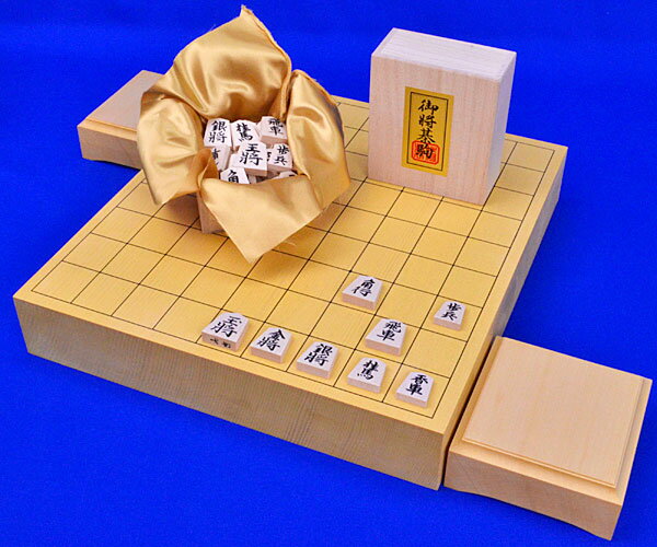 ■将棋盤：卓上将棋盤　新かや2寸一枚板 ・将棋盤の材質： 　木製　一枚板造り　新かや材（北米スプルース材） ・将棋盤のサイズ：横幅33cm×奥行36cm　厚み約6cm ■将棋駒：木製将棋駒　白椿上彫駒 ■将棋駒台：卓上将棋盤用駒台　ヒバ2寸 　卓上将棋盤新かや2寸一枚板と木製将棋駒白椿上彫駒と卓上将棋盤用駒台ヒバ2寸との木製将棋盤セットです。 　卓上将棋盤新かや2寸一枚板は新かや材(北米スプルース材)の一枚板造りの厚みが2寸の卓上将棋盤です。明るい白黄褐色系の色合いです。 　本榧やヒバ・本桂・新桂などの他の木材の将棋盤よりも新かや将棋盤はややソフトな指し味で、すっきりとした見やすい明るい色合いが特徴です。通常卓上将棋盤はハギ造り（一枚板造りではなく角材の合板造り）が主流ですが、こちらの新かや2寸一枚板卓上将棋盤は一枚板造りでどことなくすっきりした感じもお楽しみいただけます。 　将棋駒白椿上彫駒はやや軽量な将棋駒ですっきりと見やすい基本書体の彫り字の木製将棋駒です。指し味はシャム黄楊将棋駒や本黄楊将棋駒には及びませんが、彫り字なので字が薄くなることがほとんどなく、書き駒や押し駒よりも高級感があり、リーズナブルで見やすい書体がウリの人気の普及木製将棋駒です。 　手軽ですがすっきり見やすい白椿上彫駒とのリーズナブルな新かや2寸一枚板卓上将棋盤セットです。