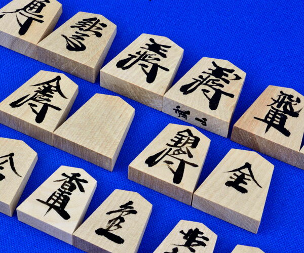　木製将棋駒の斧折漆書駒です。将棋駒の木地は斧折（おのおれ）材で日本伝統的な書体での漆書きの将棋駒です。 　斧折材は、斧が折れるほど堅い木という由来からの名の木材で、指し味の良い将棋駒として歴史の長いシャム黄楊材に近い質感があり、指し味もしっかりとお楽しみいただけます。 　明るい色合いのシャム黄楊将棋駒と比べると斧折将棋駒はやや赤みを帯びたうっすらとした茶褐色系の色合いです。使うほどに心もち深みのある色合いになります。 　将棋駒斧折漆書駒は指し味をお楽しみいただけるリーズナブルな木製将棋駒で、日本伝統的な味わいある書体の漆書きの将棋駒で独特の雰囲気もお楽しみ頂けるかと存じます。