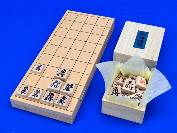 将棋セット　小型新桂4号折将棋盤セット(木製将棋駒アオカ押し駒) ■将棋盤：小型折将棋盤新桂4号 ・将棋盤の材質：木製折盤　新桂材(アガチス材) ・将棋盤のサイズ：横幅26cm×奥行30cm　厚み約1.2cm ※将棋盤の正規の天面サイズ：横幅33cm×奥行36cm ■将棋駒：木製将棋駒　アオカ押し駒 　木製折りたたみ式の小型折将棋盤新桂4号と木製将棋駒アオカ押し駒との将棋セットです。 ■折将棋盤の造り 　将棋対局時に蝶番でテーブルに傷が付くのを少しでも防ぐ為に、折将棋盤を広げても完全に平らな状態ではなく、将棋盤の中央部分が少し浮くような造りになっています。 　小型折将棋盤新桂4号は正規の将棋盤よりも天面サイズがかなり小さいタイプの将棋盤なので、将棋駒を置いた時に升目にあまりゆとりがなく、ご自宅用というよりは携帯向きの折将棋盤です。 　将棋駒アオカ押し駒はやや軽量な押し字の木製将棋駒で、やや太字で基本書体の見やすい字の人気の普及木製将棋駒です。将棋駒の表面の字が黒字で裏面の字は朱字なので将棋のルールの「成る」をこども様や将棋初心者・入門者が覚えるのにも便利な将棋駒です。 　こちらの将棋セットはご自宅での将棋対局用としては将棋盤の天面が小さくて少し物足りないかもしれませんがあまりかさばらない携帯便利な木製の小型の将棋セットです。 将棋駒台　折将棋盤用駒台　新桂