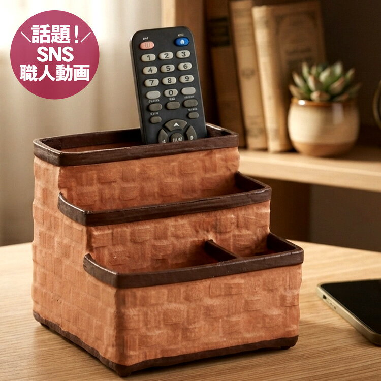 ■サイズ：約W14.5×H13×D14.5cm ■重さ：約130g ■素材：真竹、和紙（楮100％）、柿渋 ■原産国：日本製・国産 一閑張り 一閑張 国産 日本製 竹製 竹細工 竹工芸 竹製品 リモコンラック リモコンスタンド リモコン収納 スマホラック スマホスタンド スマートフォン 携帯 電話 小物入れ 小物収納 卓上収納 収納ラック 整理 整頓 三段 仕切り 和風 和モダン インテリア デスク リビング 天然素材 伝統工芸暮らしを整える一閑張り 真竹の四ツ目編みの上に丁寧に和紙を貼り、柿渋で仕上げられた温もりや、やさしさを感じる一閑張りの小物入れ。段差のある収納で、リモコンやスマートフォンなど、身の回りの小物をすっきりひとまとめに。机や棚の上に置くだけで、散らかりがちな日常を心地よく整えます。 柿渋、五回塗布仕上げ 耐久性と風合いを醸し出すために職人は妥協しません。柿渋を五回塗り重ねるのは、中学時代から学んだ頑固な父親譲りの技法です。 楮100％の風合い 楮（こうぞ）特有の繊維のからみがあり、表皮に若干のケバ立ちが出来る場合もありますが工業的に生産されたパルプとは違う、昔ながらの楮100％の和紙にこだわり製作しています。手で触れると心地のよい和紙の風合いを感じられます。特別な棕櫚束子（しゅろたわし）で、楮和紙から竹編みが浮かび上がる表情を出すために丁寧に仕上げました。 竹編み×一閑張り加工の技 国産の竹編み 竹編みの素地には、海外製の籠を使う場合がほとんどですが、素地から伝統の日本の職人にこだわり製作しました。和紙で隠れてしまうと思われがちですが、和紙貼りの下から浮かび上がる美しい竹ヒゴのラインは熟練職人の技を感じる仕上がりです。 重ね貼りと柿渋仕上げ 下地の和紙の上に色付きの和紙に糊付けし、シワに気をつけながら貼り付けます。和紙を貼り付け乾燥させた後は、いよいよ仕上げの柿渋塗布。柿渋を使うことにより、更に強度をまし長くご愛用いただける丈夫な籠となるのです。 竹・和紙・柿渋 日本に昔からあって、ずっと使われてきた素材たち。だからでしょうか。竹、和紙、柿渋で作られた一閑張りは使ったことがなくても、どこか懐かしさがあり、温もりがあり、心の安らぎを感じるのです。手作りのため一つ一つ色合いに違いがあります。 細部までこだわる色の切り替え 縁部分は濃い色に切り替え、全体を引き締めるアクセントに。色を切り替える幅も細く仕上げ、すっきりと上品に見えるようこだわっています。また、仕切りのある複雑な形ながら、内側にも一つひとつ丁寧に和紙を貼り仕上げました。細かな部分にまで、一閑張りならではの手仕事が息づいています。 サイズ 天然素材を手作りしておりますので、形や色目、大きさが写真と若干違う場合があります。 ※ご注意ください シワや柿渋の染みや色むら、歪み、和紙の切れ目が筋の様に見える場合がございます。柿渋は使うほどに濃い色合いに変化し、だんだんと目立たなくなりますので、経年変色を楽しみながらご愛用ください。 ※保管方法 保管の際には直射日光を避け、風通しの良い場所でお願いいたします。ビニール袋など通気性の悪いものにいれての保管はカビの原因となりますのでご注意ください。