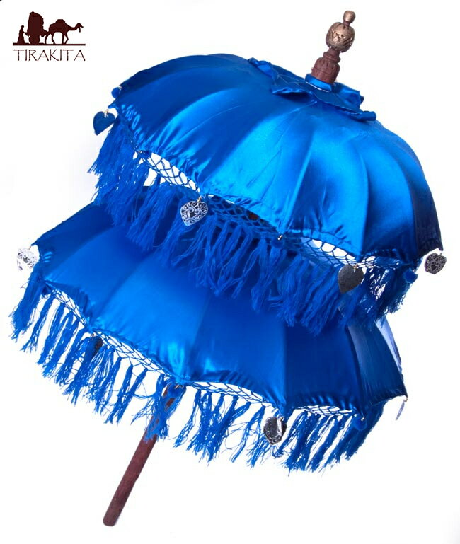 ■バリの2段の傘(青) - 70cmと80cmの詳細 直径68?から70?程度 長さ135?程度2個目の直径80?から85?程度 重量約1.5kg程度 素材木、竹あす楽について全体写真です。傘の上の部分の写真です傘の下部の写真です傘の内側はこんな感じです色の違う傘を身長180cmのインドパパが大きさ比較のために持ってみました バリ島に行くと、神様の上や、寺院などの色々なところで見かけるバリ傘です。カラフルで、綺麗で、原色で赤道直下という感じですね。当店のイベントDANCE OF SHIVAでも使用し、中にカラー電球を入れることによって大変幻想的な空間を演出しています。扉の前に2つ斜めに刺しておくだけで、雰囲気が一気にアジア風、バリ風に変わる簡単アイテムです。 夏の熱い日に日傘として…はちょっと重いかもしれませんが、全部木と竹で作られているので無理な感じではないです。イベント時のデコレーションに、仮装の時のアクセントに、野外イベントに行った時の目印に、お店のデコレーションに、開くだけで簡単にアジア風になる素敵な一品です