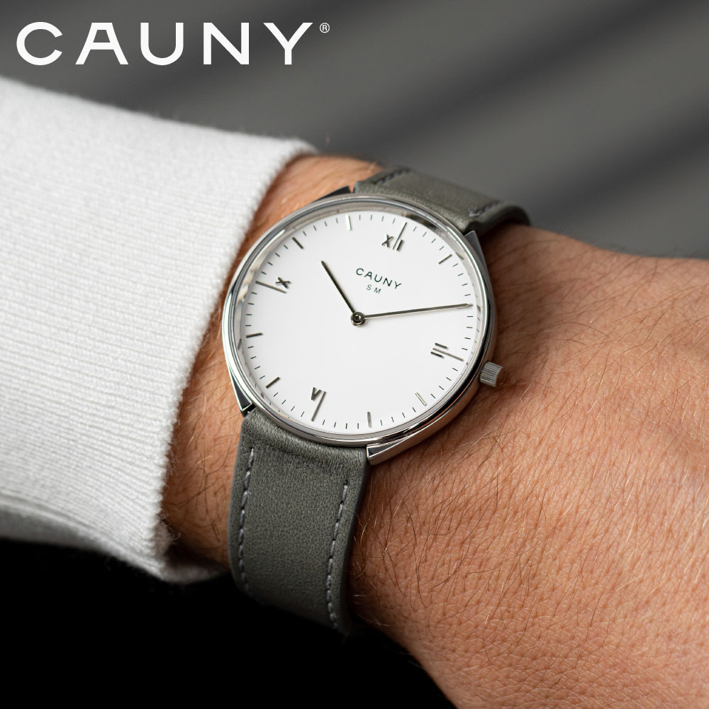 BRAND - CAUNY 建築界のノーベル賞とも言われているプリツカー賞を受賞した世界最高峰の名建築家たちと、フリーハンドのデッサンから腕時計を創り上げていくプロジェクト「Architects of Time」。このプロジェクトはスイスで約100年の歴史をもち、常にユニークな時計の開発を続けてきた腕時計ブランド「CAUNY」が2022年に立ち上げました。商品説明 The Architects of Time 建築界のノーベル賞「プリツカー賞」を受賞した世界の建築家がデザインを手がける腕時計ブランドCAUNYの「The Architects of Time（アーキテクツ オブ タイム）」。 スイスで約100年の歴史をもち、常にユニークな時計の開発を続けてきた腕時計ブランドCAUNY（カウニー）は、2022年、現代最高の建築家たちと腕時計を開発するプロジェクト「 Architects of Time（アー キテクツ・オブ・タイム）」を立ち上げました。 このプロジェクトは著名な建築家にとっても新しい挑戦でした。 ただの時計ではなく、「時間」を表現することこそがこのプロジェクトのテーマです。 流れ続ける時間を1つのプロダクトとして表現した腕時計は、まるで身に着けるアート作品の様です。 これまでに様々な名建築を世界に残してきた安藤忠雄をはじめ、アルヴァロ・シザ（ポルトガル）、ラファエル・モネオ（スペイン）、ソウト・モウラ（ポルトガル）等、自身の手でスケッチから起こしたデザインが、腕時計の形となってリリースされるのはこれが世界で初めてです。 この時計が好きなのは、シンプルで、時間がはっきり見え、建物のようだから。まずは美しくなければならず、機能するならさらに良い。 ソウト・モウラのサインが入ったグレーの文字盤は、12、3、6、9の位置に細長いローマ数字を軸として配置しています。 ドーム型の風防はサファイアクリスタル、ケース上部と側面でポリッシュとブラッシュの仕上げを使い分け、テクスチャーの遊び心を表現しています。 拘りの形状でありながらシンプルなこのケースに、ストラップが隙間なくフィットすることで時計を一体型にしています。 根元からサイン入りのバックルまでテーパードされたストラップはエレガントな印象を与えてくれます。 Souto Moura（ソウト・モウラ） ソウト・モウラは1952年 ポルトガル生まれ。 ポルト高等美術学校を卒業し、生涯を通じてフェルナンド・タヴォラとアルヴァロ・シザという2人の重要な巨匠から学びました。 彼の作品は、個人と公共建築の両方を網羅し、初の作品でもある、ポルト、セラ・ダ・アラビダ、モレドのヴィラが有名です。 最大の建物としては、ブラガ市営スタジアムを設計、これは、間違いなく世界で最も美しいサッカースタジアムです。 ソウト・モウラは、その卓越した能力とセンスを長い学問的キャリアにも生かし、パリ・ベルヴィル建築学部、ハーバード大学、チューリッヒ工科大学、ローザンヌ建築学部などを渡り歩いています。 2011年には世界的な功績が認められプリツカー賞を受賞し、その後も数々の国際的な賞や表彰の頂点に立っています。 CAUNY（カウニー）についてモウラのコメント 「この時計が好きなのは、シンプルで時間もはっきりわかるし、建物のようなものだからです。シンプルで機能的で、できれば美しくなければなりません。」 About CAUNY 1927年、スイスで誕生したカウニーは、ポーランド移民グレブラー家の三兄妹によって創業された時計ブランド。 エレガントで革新的なデザインとスイス品質を両立し、50〜70年代には世界中で愛されました。 手頃な価格と高品質を両立する製造精神を受け継ぎながら、カウニーは100年近くにわたり、伝統と革新を融合させた時計づくりを続けています。 スペック ケース：ステンレススチール316L 風防：サファイアガラス ストラップ：ジャーマンレザー ストラップ幅：19mm ムーブメント：クオーツ 防水：3ATM サイズ：径38mm/厚7mm 腕回り：約約14〜19.5cm 正規保証：2年 付属品：正規保証書