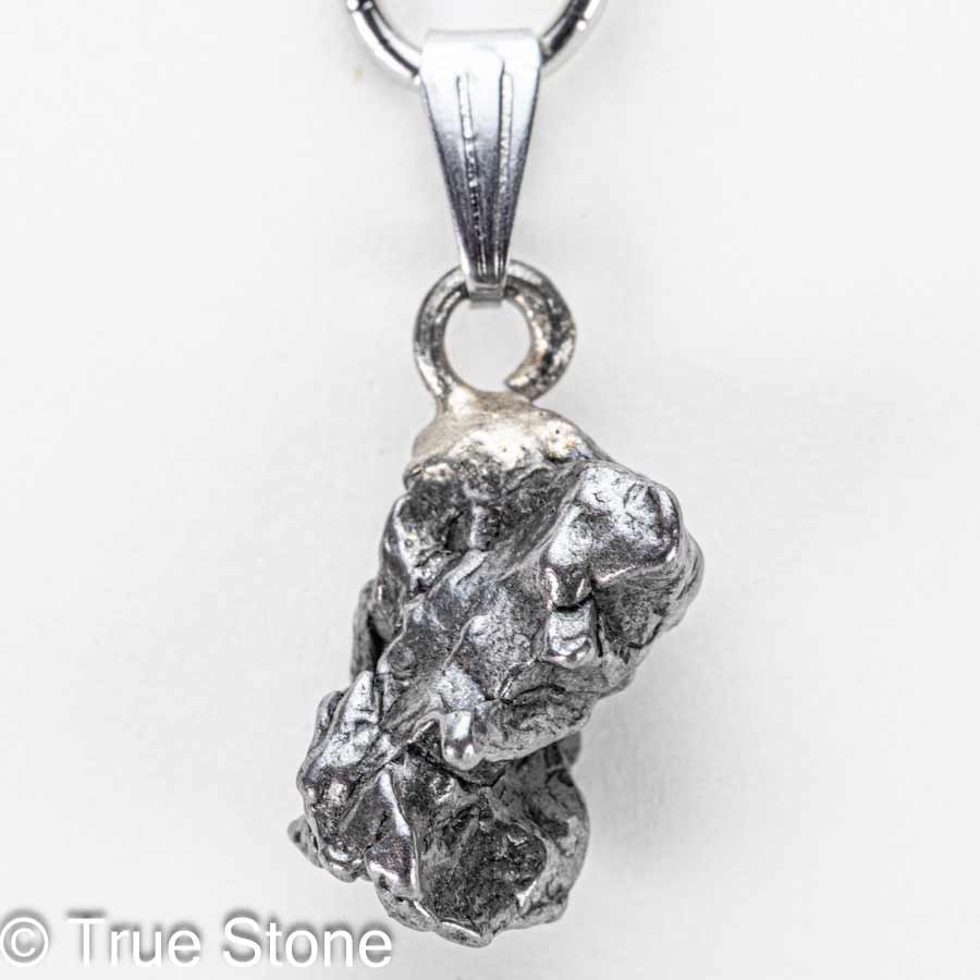 小さな頃、願い事を叶えたい一心で夜空を見上げ「流れ星」を探していたあの日。 不思議と「探す」と見つかりません。 偶然「流れ星」を発見しても、「あっ」と思った瞬間燃え尽きていたあの日。 そういう時に限って「願い事」は忘れています。 それなら、隕石（流れ星）を実際に手に入れて願ってみてはいかがでしょうか。 昔なら「流れ星」を手に入れる事こそが「願い事」だったのかもしれません。 そんな子供の頃の夢や希望が内包する「流れ星」を両手で握りしめると、「当時の自分」を垣間見る事ができるかもしれません。 カンポ・デル・シエロ隕石は、アルゼンチン北部のチャコ州からサンティアゴ・デル・エステーロ州にかけて広がる巨大な隕石散在域で見つかる鉄隕石で、名前はスペイン語で「天の野原（天空の野）」を意味します。 この地帯には数千年前に大規模な隕石の落下が起きたと考えられており、地表には大小のクレーターが点在し、その周囲から無数の破片が採集されてきました。 先住民の伝承や16世紀以降の記録にも「鉄の塊」の存在が語られており、近代的な地質調査によって、広範囲に散らばった鉄隕石群であることが確かめられています。 分類上はIABグループに属する鉄隕石で、主成分は鉄とニッケルの合金です。 ニッケルはおよそ6〜7％前後を含み、これに硫化鉄（トロイライト）、リン化物（シュライバーサイト）、炭化物（コーエン石）などの包有物が散点するため、切断面や破断面に複雑で味わい深い表情を与えます。 内部組織は「オクタヘドライト（八面体構造）」で、適切に研磨・酸エッチングされたスライスでは、カマサイトとテーナイトが幾何学的に組み合わさった有名なウィドマンシュテッテン構造が現れます。 この幾何学模様は、地球上では自然条件下で再現できない極めて遅い冷却過程（数千万〜数億年スケール）でのみ形成されるため、カンポ・デル・シエロをはじめとする鉄隕石の「宇宙由来」の証拠として珍重されています。 大きな個体（ナチュラル・ピース）の外観は、表面に親指で押し込んだような「レグマグリプツ（拇指状凹）」が刻まれていることが多く、これは大気圏突入時の高温・高圧下で溶融と剥離が繰り返された痕跡と解釈されます。 流線痕や溶融皮殻が部分的に残る標本もあり、手のひらサイズでも密度が高く、見た目以上の重量感があるため初見の方は必ずといっていいほど「想像より重い」と驚かれます。 市場では二つの形態が流通します。 ひとつは自然形状を保った個体で、レグマグリプツや溶融痕、自然酸化の風合いをそのまま楽しむコレクション向けのタイプです。 もうひとつは小さなカンポデルシエロをそのままの状態でペンダント等へ利用するジュエリー素材として高い人気を誇ります。 カンポ・デル・シエロは屋外で長期間にわたり風化してきた経緯から、塩化物に起因する錆「隕石病」が進行しやすい個体もあります。 コレクションやジュエリーとして長く楽しむためには、湿気と塩分を避け、素手で触れた後は柔らかい布で油分と汗を拭き取り、乾燥剤を入れた密閉容器で保管するのが基本ですがカメラ用防湿庫があれば最適です。 ※当店では隕石に錆止めスプレーを施し、カメラ用防湿庫に湿度10％〜20％で保存しています。 パワーストーンの観点では、カンポ・デル・シエロは「地球外の鉄（宇宙鉄）」としてグラウンディングと意志力の強化、行動力の点火を象徴すると語られることがあります。 科学的効能を保証するものではありませんが、何十億年の時間を経てきた物質を手にする体験は、創作や決断の背中を押す“物語性の力”をもたらしてくれるでしょう。 総じて、カンポ・デル・シエロ隕石は、学術的にも審美的にも「鉄隕石の醍醐味」を一本で味わえるオールラウンダーです。 自然のレグマグリプツを残した個体は荒々しい宇宙の息遣いを、エッチングしたスライスは宇宙時間の結晶学を、それぞれ手のひらサイズで見せてくれます。 本品は研磨や酸処理を一切施していない、自然なままの隕石です。 鉄隕石は本来、黒みを帯びた風合いを持ちます。 市場では金属光沢を強調するために表面を研磨・酸洗いした隕石も流通していますが、こちらは地球に落ちたままの姿を残した貴重な一点物。 ... 以下の写真は当店で取得したカンポ・デル・シエロ隕石の宝石鑑別書の一例です。 当店ではカンポ・デル・シエロ鉄質隕石に鑑別書をお付けする事が可能ですので、お気軽にご相談下さいませ。 本品は1点物でお写真の隕石が届きます。 価格がお安くてもランダム発送品ではどのような形の物が届くかが分からないため購入に踏み切れないと言う声にお答えしました。 天然石だけではなく隕石も形が重要です。 ご自身で「これだ」と思える逸品を選んで下さい。 そこからが「あなた」と「小さな流れ星」との出会いの始まりです。 【お写真に写っている商品を発送致します】 バチカン　ステンレス鋼 開口サイズ　約6mm×3mm程度 縦　約28mm（バチカン込みでの測定） 横　約12mm 厚さ　約9mm 重量　約4.7g 天然隕石のため黒ずみ、サビ等がある場合がございます。 錆び防止のため「錆止めスプレー」をしてカメラ用放湿庫に保存していますので若干錆止めの匂いが残る可能性がございます。 尚、水や汗に弱いのでお取り扱いにはご注意下さいませ。 カンポデルシエロ隕石　鑑別書2通届きました 天然石の本物・偽物を見極める「鑑別書」 True Stone 天然石の真実