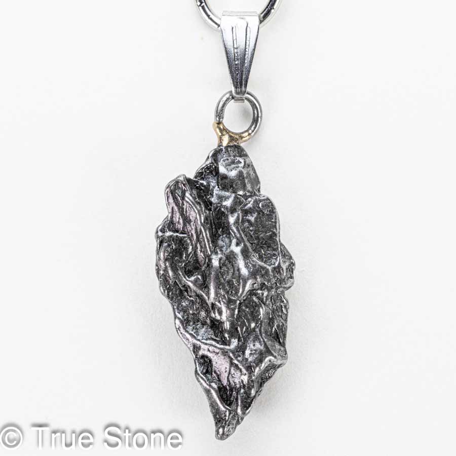 小さな頃、願い事を叶えたい一心で夜空を見上げ「流れ星」を探していたあの日。 不思議と「探す」と見つかりません。 偶然「流れ星」を発見しても、「あっ」と思った瞬間燃え尽きていたあの日。 そういう時に限って「願い事」は忘れています。 それなら、隕石（流れ星）を実際に手に入れて願ってみてはいかがでしょうか。 昔なら「流れ星」を手に入れる事こそが「願い事」だったのかもしれません。 そんな子供の頃の夢や希望が内包する「流れ星」を両手で握りしめると、「当時の自分」を垣間見る事ができるかもしれません。 カンポ・デル・シエロ隕石は、アルゼンチン北部のチャコ州からサンティアゴ・デル・エステーロ州にかけて広がる巨大な隕石散在域で見つかる鉄隕石で、名前はスペイン語で「天の野原（天空の野）」を意味します。 この地帯には数千年前に大規模な隕石の落下が起きたと考えられており、地表には大小のクレーターが点在し、その周囲から無数の破片が採集されてきました。 先住民の伝承や16世紀以降の記録にも「鉄の塊」の存在が語られており、近代的な地質調査によって、広範囲に散らばった鉄隕石群であることが確かめられています。 分類上はIABグループに属する鉄隕石で、主成分は鉄とニッケルの合金です。 ニッケルはおよそ6〜7％前後を含み、これに硫化鉄（トロイライト）、リン化物（シュライバーサイト）、炭化物（コーエン石）などの包有物が散点するため、切断面や破断面に複雑で味わい深い表情を与えます。 内部組織は「オクタヘドライト（八面体構造）」で、適切に研磨・酸エッチングされたスライスでは、カマサイトとテーナイトが幾何学的に組み合わさった有名なウィドマンシュテッテン構造が現れます。 この幾何学模様は、地球上では自然条件下で再現できない極めて遅い冷却過程（数千万〜数億年スケール）でのみ形成されるため、カンポ・デル・シエロをはじめとする鉄隕石の「宇宙由来」の証拠として珍重されています。 大きな個体（ナチュラル・ピース）の外観は、表面に親指で押し込んだような「レグマグリプツ（拇指状凹）」が刻まれていることが多く、これは大気圏突入時の高温・高圧下で溶融と剥離が繰り返された痕跡と解釈されます。 流線痕や溶融皮殻が部分的に残る標本もあり、手のひらサイズでも密度が高く、見た目以上の重量感があるため初見の方は必ずといっていいほど「想像より重い」と驚かれます。 市場では二つの形態が流通します。 ひとつは自然形状を保った個体で、レグマグリプツや溶融痕、自然酸化の風合いをそのまま楽しむコレクション向けのタイプです。 もうひとつは小さなカンポデルシエロをそのままの状態でペンダント等へ利用するジュエリー素材として高い人気を誇ります。 カンポ・デル・シエロは屋外で長期間にわたり風化してきた経緯から、塩化物に起因する錆「隕石病」が進行しやすい個体もあります。 コレクションやジュエリーとして長く楽しむためには、湿気と塩分を避け、素手で触れた後は柔らかい布で油分と汗を拭き取り、乾燥剤を入れた密閉容器で保管するのが基本ですがカメラ用防湿庫があれば最適です。 ※当店では隕石に錆止めスプレーを施し、カメラ用防湿庫に湿度10％〜20％で保存しています。 パワーストーンの観点では、カンポ・デル・シエロは「地球外の鉄（宇宙鉄）」としてグラウンディングと意志力の強化、行動力の点火を象徴すると語られることがあります。 科学的効能を保証するものではありませんが、何十億年の時間を経てきた物質を手にする体験は、創作や決断の背中を押す“物語性の力”をもたらしてくれるでしょう。 総じて、カンポ・デル・シエロ隕石は、学術的にも審美的にも「鉄隕石の醍醐味」を一本で味わえるオールラウンダーです。 自然のレグマグリプツを残した個体は荒々しい宇宙の息遣いを、エッチングしたスライスは宇宙時間の結晶学を、それぞれ手のひらサイズで見せてくれます。 本品は研磨や酸処理を一切施していない、自然なままの隕石です。 鉄隕石は本来、黒みを帯びた風合いを持ちます。 市場では金属光沢を強調するために表面を研磨・酸洗いした隕石も流通していますが、こちらは地球に落ちたままの姿を残した貴重な一点物。 ... 以下の写真は当店で取得したカンポ・デル・シエロ隕石の宝石鑑別書の一例です。 当店ではカンポ・デル・シエロ鉄質隕石に鑑別書をお付けする事が可能ですので、お気軽にご相談下さいませ。 本品は1点物でお写真の隕石が届きます。 価格がお安くてもランダム発送品ではどのような形の物が届くかが分からないため購入に踏み切れないと言う声にお答えしました。 天然石だけではなく隕石も形が重要です。 ご自身で「これだ」と思える逸品を選んで下さい。 そこからが「あなた」と「小さな流れ星」との出会いの始まりです。 【お写真に写っている商品を発送致します】 バチカン　ステンレス鋼 開口サイズ　約6mm×3mm程度 縦　約39mm（バチカン込みでの測定） 横　約13.1mm 厚さ　約6.5mm 重量　約6.1g 天然隕石のため黒ずみ、サビ等がある場合がございます。 錆び防止のため「錆止めスプレー」をしてカメラ用放湿庫に保存していますので若干錆止めの匂いが残る可能性がございます。 尚、水や汗に弱いのでお取り扱いにはご注意下さいませ。 カンポデルシエロ隕石　鑑別書2通届きました 天然石の本物・偽物を見極める「鑑別書」 True Stone 天然石の真実