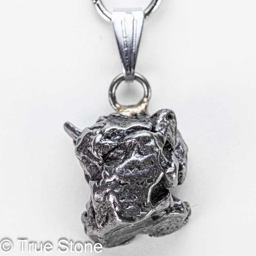 小さな頃、願い事を叶えたい一心で夜空を見上げ「流れ星」を探していたあの日。 不思議と「探す」と見つかりません。 偶然「流れ星」を発見しても、「あっ」と思った瞬間燃え尽きていたあの日。 そういう時に限って「願い事」は忘れています。 それなら、隕石（流れ星）を実際に手に入れて願ってみてはいかがでしょうか。 昔なら「流れ星」を手に入れる事こそが「願い事」だったのかもしれません。 そんな子供の頃の夢や希望が内包する「流れ星」を両手で握りしめると、「当時の自分」を垣間見る事ができるかもしれません。 カンポ・デル・シエロ隕石は、アルゼンチン北部のチャコ州からサンティアゴ・デル・エステーロ州にかけて広がる巨大な隕石散在域で見つかる鉄隕石で、名前はスペイン語で「天の野原（天空の野）」を意味します。 この地帯には数千年前に大規模な隕石の落下が起きたと考えられており、地表には大小のクレーターが点在し、その周囲から無数の破片が採集されてきました。 先住民の伝承や16世紀以降の記録にも「鉄の塊」の存在が語られており、近代的な地質調査によって、広範囲に散らばった鉄隕石群であることが確かめられています。 分類上はIABグループに属する鉄隕石で、主成分は鉄とニッケルの合金です。 ニッケルはおよそ6〜7％前後を含み、これに硫化鉄（トロイライト）、リン化物（シュライバーサイト）、炭化物（コーエン石）などの包有物が散点するため、切断面や破断面に複雑で味わい深い表情を与えます。 内部組織は「オクタヘドライト（八面体構造）」で、適切に研磨・酸エッチングされたスライスでは、カマサイトとテーナイトが幾何学的に組み合わさった有名なウィドマンシュテッテン構造が現れます。 この幾何学模様は、地球上では自然条件下で再現できない極めて遅い冷却過程（数千万〜数億年スケール）でのみ形成されるため、カンポ・デル・シエロをはじめとする鉄隕石の「宇宙由来」の証拠として珍重されています。 大きな個体（ナチュラル・ピース）の外観は、表面に親指で押し込んだような「レグマグリプツ（拇指状凹）」が刻まれていることが多く、これは大気圏突入時の高温・高圧下で溶融と剥離が繰り返された痕跡と解釈されます。 流線痕や溶融皮殻が部分的に残る標本もあり、手のひらサイズでも密度が高く、見た目以上の重量感があるため初見の方は必ずといっていいほど「想像より重い」と驚かれます。 市場では二つの形態が流通します。 ひとつは自然形状を保った個体で、レグマグリプツや溶融痕、自然酸化の風合いをそのまま楽しむコレクション向けのタイプです。 もうひとつは小さなカンポデルシエロをそのままの状態でペンダント等へ利用するジュエリー素材として高い人気を誇ります。 カンポ・デル・シエロは屋外で長期間にわたり風化してきた経緯から、塩化物に起因する錆「隕石病」が進行しやすい個体もあります。 コレクションやジュエリーとして長く楽しむためには、湿気と塩分を避け、素手で触れた後は柔らかい布で油分と汗を拭き取り、乾燥剤を入れた密閉容器で保管するのが基本ですがカメラ用防湿庫があれば最適です。 ※当店では隕石に錆止めスプレーを施し、カメラ用防湿庫に湿度10％〜20％で保存しています。 パワーストーンの観点では、カンポ・デル・シエロは「地球外の鉄（宇宙鉄）」としてグラウンディングと意志力の強化、行動力の点火を象徴すると語られることがあります。 科学的効能を保証するものではありませんが、何十億年の時間を経てきた物質を手にする体験は、創作や決断の背中を押す“物語性の力”をもたらしてくれるでしょう。 総じて、カンポ・デル・シエロ隕石は、学術的にも審美的にも「鉄隕石の醍醐味」を一本で味わえるオールラウンダーです。 自然のレグマグリプツを残した個体は荒々しい宇宙の息遣いを、エッチングしたスライスは宇宙時間の結晶学を、それぞれ手のひらサイズで見せてくれます。 本品は研磨や酸処理を一切施していない、自然なままの隕石です。 鉄隕石は本来、黒みを帯びた風合いを持ちます。 市場では金属光沢を強調するために表面を研磨・酸洗いした隕石も流通していますが、こちらは地球に落ちたままの姿を残した貴重な一点物。 ... 以下の写真は当店で取得したカンポ・デル・シエロ隕石の宝石鑑別書の一例です。 当店ではカンポ・デル・シエロ鉄質隕石に鑑別書をお付けする事が可能ですので、お気軽にご相談下さいませ。 本品は1点物でお写真の隕石が届きます。 価格がお安くてもランダム発送品ではどのような形の物が届くかが分からないため購入に踏み切れないと言う声にお答えしました。 天然石だけではなく隕石も形が重要です。 ご自身で「これだ」と思える逸品を選んで下さい。 そこからが「あなた」と「小さな流れ星」との出会いの始まりです。 【お写真に写っている商品を発送致します】 バチカン　ステンレス鋼 開口サイズ　約6mm×3mm程度 縦　約26mm（バチカン込みでの測定） 横　約13.3mm 厚さ　約9.1mm 重量　約7g 天然隕石のため黒ずみ、サビ等がある場合がございます。 錆び防止のため「錆止めスプレー」をしてカメラ用放湿庫に保存していますので若干錆止めの匂いが残る可能性がございます。 尚、水や汗に弱いのでお取り扱いにはご注意下さいませ。 カンポデルシエロ隕石　鑑別書2通届きました 天然石の本物・偽物を見極める「鑑別書」 True Stone 天然石の真実