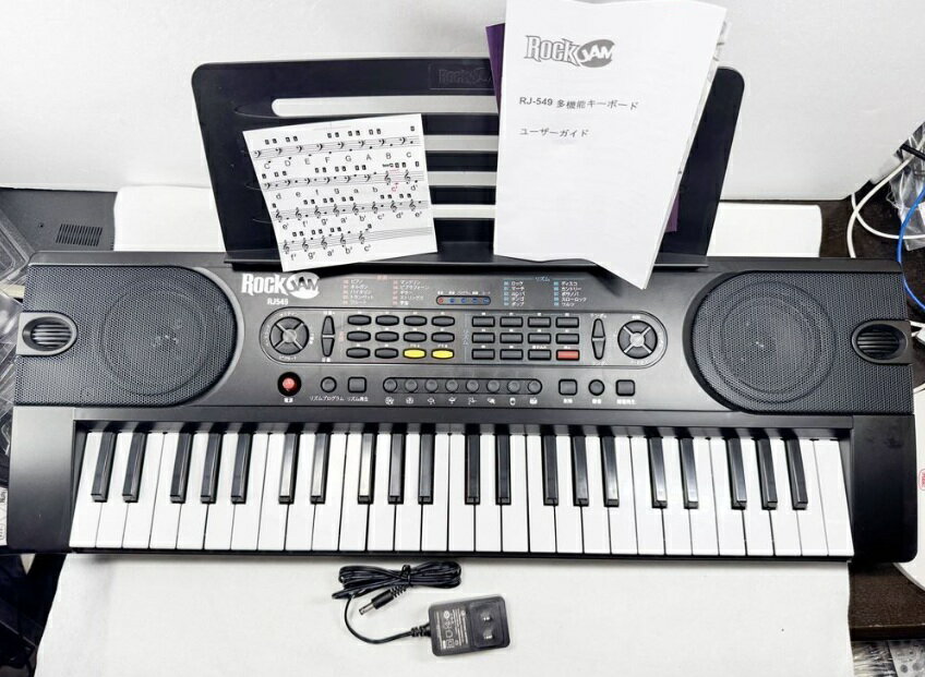 RockJam ロックジャム RJ549 電子キーボード 49鍵盤 多彩な音とリズム LEDディスプレイ 録音再生機能 ACアダプタ付属 初心者向け 商　品　説　明 動作確認済み。簡易清掃するほど汚れてません。目立った傷、スレ、汚れ等は有りません。細かい傷、スレ、汚れ等も有りません。未使用に近い美品です。付属品は電子キーボード以外にはACアダプター（DC 9V、 1000mA）、譜面立て（ミュージックスタンド）、鍵盤ステッカー（キーラベル）、ユーザーマニュアル（取扱説明書）が付属します。予めご理解ご了承の上お買い求めください。発送は商品を簡易包装して発送いたします。1. RockJam ブランドのポータブル電子キーボード 2. 鍵盤数：49鍵盤でコンパクトながら必要な音域をカバー 3. 多彩な音色とリズム：10種類の音色、10種類のリズム、8種類のパーカッション音を搭載 4. 録音・再生機能：最大40ノートのレコーディングと再生が可能 5. LEDディスプレイ搭載：演奏状況やモードを簡単に確認可能 6. 内蔵ステレオスピーカー：音量16段階調節可能 7. 電源方式：ACアダプター（DC 9V、 1000mA）または単三乾電池6本（別売り）対応 8. 付属品：ACアダプター、譜面立て、鍵盤ステッカー、取扱説明書 9. サイズ・重量：幅約698mm × 奥行約235mm × 高さ約84mm、重さ約1.66kg 10. 対応アプリ：Simply Pianoアプリで学習・練習をサポート 商　品　仕　様 メーカー名 &nbsp;アマゾンジャパン 商品分類 &nbsp;電子キーボード 商品名 &nbsp;− 型番 &nbsp;RJ549 色 &nbsp;− 定価 &nbsp;− サイズ &nbsp;幅：約698mm × 奥行：約235mm × 高さ：約84mm 重さ &nbsp;約1.66kg 素材 &nbsp;− JAN &nbsp;5025087002728 保　証　に　つ　い　て ■メーカー保証なし記載の注意事項を除く初期不良品の場合のみ、商品到着から1週間以内のみ対応いたします。ご到着後はお早めに商品状態をご確認ください。 注　意　事　項 ●こちらの商品は、中古品です。●モニター環境により、実際のカラーと異なって見える場合がございます。 ★この商品は発送先が北海道、沖縄、離島の場合は注文金額により以下の送料が必要です。・北海道の場合、注文金額が3,980円未満は880円、3,980円以上は送料無料です。・沖縄、離島の場合、注文金額が9,800円未満は880円、9,800円以上は送料無料です。