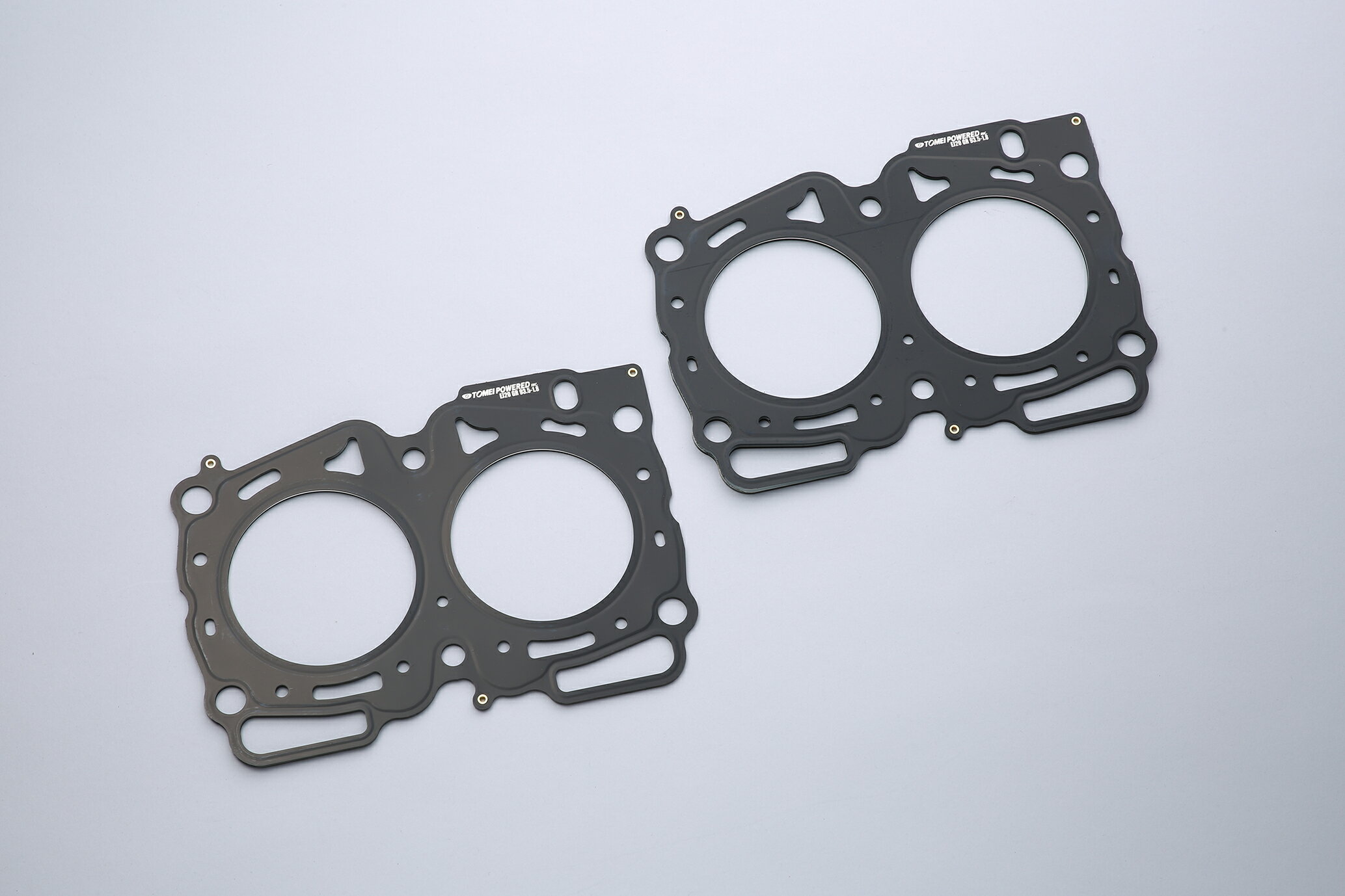 TOMEI 東名パワード HEAD GASKET ヘッドガスケット メタル EJ255 06-08 WRX EJ257 WRX STI 04- Φ101.2-1.5mm (1361101151) 商品内容 商品名：HEAD GASKET EJ255 06-08 WRX/EJ257 WRX STI 04+ 101.2-1.5mm 適合：EJ255 06-08 WRX EJ257 WRX STI 04- ボア径：φ101.2 厚さ：1.5mm 品番：1361101151 定価：￥31,000 (税抜) 材質：メタル 構造：スーパーグロメット 備考：2枚セット FEATURE / SPEC ■ スーパーグロメット採用 純正品の素材は非メタル系。構造がグロメットタイプでシール性能が不足しています。 TOMEIヘッドガスケットシリーズは信頼性抜群のスーパーグロメットタイプを採用することにより、シール性能が向上します。 スーパーグロメットタイプ ビード構造と金属グロメットのデュアルシール方式により、冷却水やオイルシールはもちろんボア外周のガスシール性を最大限に向上する。 ■ 耐熱・耐久に優れたステンレス材 追従性が良くしなやかな材質であるSUS301をビード構造表板に採用。 優れた耐熱性、耐久性を有しヘッド及びシリンダーの熱を効果的に冷却水に伝え冷却する事が可能な為、局部的に高温にならないので、吹き抜けが起こりにくいのです。また、ステンレスは引っ張り強度にも強い為、繰り返し起こるシリンダーの変形に対してもビードが追従することで吹き抜けに対して有利であり、ヘッドとブロックの結合剛性を高く出来ます。 ヘッドとブロックの結合が強固だと、エンジン全体の剛性が増し、ねじれや曲げを低減する事ができ、また運動軸受け部の耐久性が向上します。 ■ 専用リブ設計 リブを高くするとガスシール性は向上しますが、その分、周辺の冷却水やオイルのシール性が低下してしまいます。そのためパワーアップを計ると冷却水やオイルの漏れが発生することがあります。 TOMEIではスーパーグロメットタイプの採用と、リブ高さを設計から見直すことにより、全体の面圧を高く、均一に保ちシール性を向上させました。 ■ マーキングについて TOMEI製のメタルヘッドガスケットには全てに機種・ボア・厚み・TOMEIPOWERED INC. ロゴがマーキングされています。 ロゴなどを十分確認され、東名パワード製と称す模造品や類似品にご注意ください。 注意 本商品はメーカー様お取り寄せとなります。 メーカー様欠品時2〜3ヶ月以上掛かる場合がございます。 納期が長い等の理由でのキャンセルは受け付け出来かねますのでご注意くださいませ。 ※商品画像はイメージとなります。実際の商品とは異なる場合がございます。予めご了承ください。 ※別途送料頂いております。 配送業者の指定はできません。