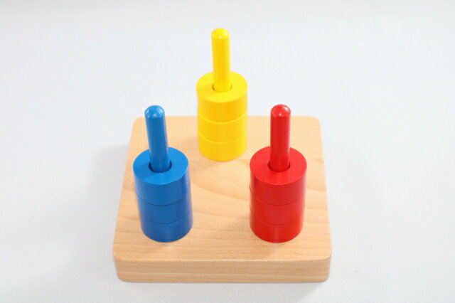 モンテッソーリ　3色リングさし ＊入荷のロッドによっては、黄色が写真よりオレンジっぽいものになります。 Montessori 3 Colored Discs on 3 Dowels 知育玩具 乳児、ヨチヨチ歩き向き Infant & Toddler 感覚教育　Sensorial 推奨年齢　6ヶ月ぐらいから90才まで。(大人も楽しいです。) 3色のディスクを3本の棒に通します。指で掴んでディスク(リング)の中央を通すという行為は、子供のモーター・スキルとともに、いわゆるハンド・アイ・コーディネーション(目と手の協応動作)を高めます。 大きさ：横15 x 縦13.5 x 高さ 13cm ** 細かなモノや角があるものもありますので、3歳以下のお子様に与える際はご注意くださいませ。親の見守る前で遊ばせるようにしてください。誤飲やケガなどの責任は当店は負えません。免責にご同意いただいたうえでご購入お願い申し上げます。ゆうパックでの発送です。