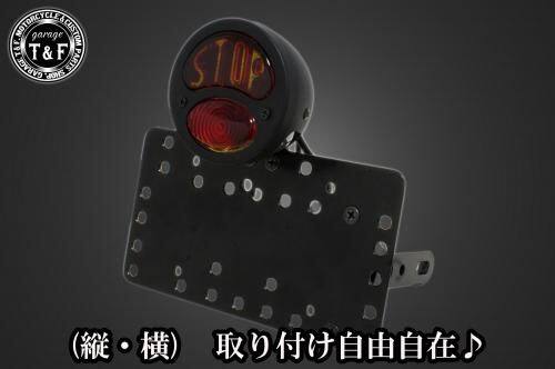 ■商品概要■本体の仕様素材：スチール製カラー：ブラック仕上げテールランプの仕様本体：スチール製色：ブラックレンズ素材：ガラス製レンズカラー：レッド発光方法：ハロゲンバルブ(12v23wと12v5wの2連)レンズサイズ：約90mm(レンズ単体での計測)ナンバー灯：有り■テールランプ取り付けステーの仕様素材：スチール製配線の役割-上のバルブ-赤色：ブレーキランプ(＋)黒色：アース(-)-下のバルブ-赤色：ポジションランプ(＋)黒色：アース(-)■詳細説明クラシックなデザインと高性能を兼ね備えた「DUOテールランプ」。愛車に高級感と安全性をプラスする理想的なパーツです！-多様な取り付け方法-通常のサイドナンバーKITでは縦固定か横固定のみですが、本製品は縦横どちらにも対応。あなたのバイクスタイルに合わせた自由なレイアウトが可能です。-細かい調整機能-取り付けステーの角度調整や前後スライド調整が出来る為、ナンバープレートの位置を思い通りにセッティング可能。細部まで理想のスタイルを実現します。横向きの場合：7か所の取り付け位置を選択可能。縦向きの場合：12か所の取り付け位置を選択可能。-ボルトオンで簡単装着-車種専用のステー付きです。加工不要で取り付け可能。■注意点※製造ロットによってテールランプの配線の色、長さが変更されることがございますので予めご了承ください。※ガレージT＆FサイドナンバーKITは取り付け位置にかなり自由度がございます。しかしながらテールランプの種類によっては取り付け位置が制限される場合がございます。※ガレージ T＆FフラットフェンダーKITと同時装着する場合も取り付け位置が制限される場合がございます。※車種によっては、別売のサイドナンバーオフセットKITが必要となる場合がありますのでご注意ください。※メーカー都合により商品の仕様変更がある場合がございます。ご了承ください。■適合車種W230&ensp;W230メグロS1&ensp;メグロS1