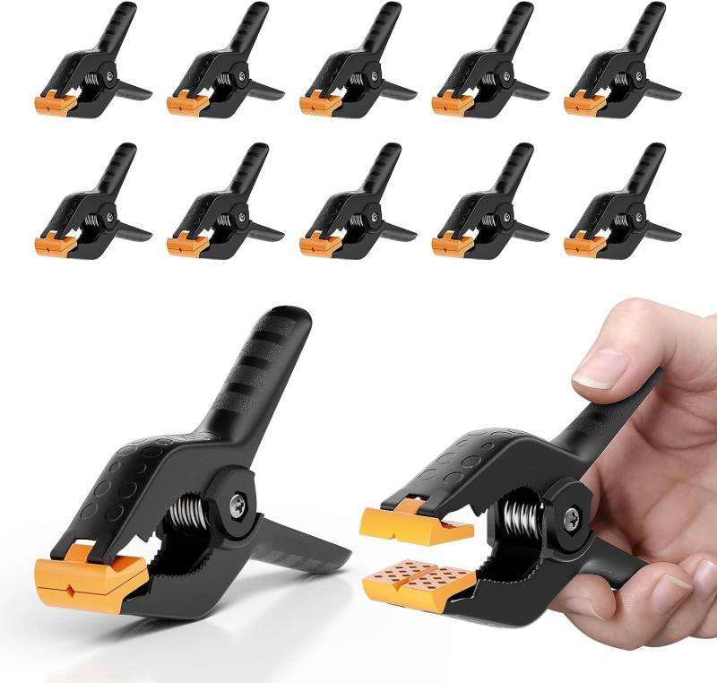 EMART スプリングクランプ 木工 12個 強力クリップ 大型 撮影 クリップ 固定 滑り止め 110*79MM 4.5インチ -ブラック&amp;オレンジ【耐久性の高い鋸歯の挟み口】背景布やバック紙の撮影作業に適した場所に、背景をしっかり固定して、滑ることも防止でき、擦り傷から守れます。クランプの両端から下の歯状の領域は、円形のものを保持するために使用することができます。回転可能なクランプは、規則や不規則なものを保持することができます。木、背景布、防水布に適しています。織物に跡がつきません。クリップは長く使っても壊れません。【滑り止めのハンドル&amp;頑丈なスプリング】粒子状の柄は摩擦力が大きくなり、手にギュッと密着力を入りやすくなる。バータースチールコイルばねは一貫したクランプ圧力を発生させ、ネジで固定することで強度と耐久性を高めます。【オレンジ色の調節パッド】オレンジ色のマットが追加のグリップを提供し、フレキシブルなマットで調整も容易です。ワイドな可動式パッドが凹凸に合わせて自動調整し、きっちりに均一に挟んで、挟まれる物の表面を保護できます。また、万が一自動調整パッドが壊れたことがある場合、交換できるように6つの追加の挟み口パットが付属しております。（ご注意：オレンジ色の部分を外側に向けないでください）【上質な素材&amp;幅広く用途】高品質なナイロンと金属素材が採用されて、強力だけでなく耐久性にも優れています。スプリングクランプは用途が広く、軽量で使いやすく、一般クラフト、大工道具、モデル作り、ホビー、木工作業、撮影、物干し等の固定作業にも応用できます。【クリップのサイズ】長さ約11cmの強力クリップの最大の開き口は約5cmで、ハンドルの幅は約7.8 cmです。他のスプリングクリップよりも大きなものです。さまざまなサイズの背景布や背景スタンドに適しています。人間工学に基づき、力を入れやすいし、手に優しいです。