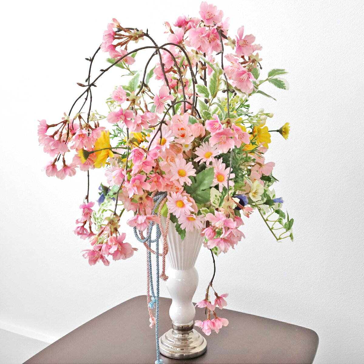 ボリュームある枝垂れ桜が目を惹くスタイリッシュなアレンジです高さがあるので、広い空間のディスプレイにもおすすめです 陶製のデコラティブな花器と組紐を合わせ、和モダンに仕上げました サイズ：約高さ52cm×幅35cm×奥行30cm＊商品の仕様は変更になる場合がございます＊受注制作のため数日お時間をいただく場合がございます シルクフラワーとは、シルクの様な光沢のある生地を用いて作られ、 生花のような花びらのグラデーション・葉や茎の樹皮や節までリアルを追求した高品質な人工的な花のことをいいます。 他にも、一般的な造花を指すアートフラワーと呼ばれることもあります。 また、近年では呼び名が統一され、生花の代わりとなる人口的な花のことを全てまとめてアーティフィシャルフラワーと呼ばれる様になりました。 ☆ギフト対応の詳細はこちら シルクフラワーのグレードアップアイテム♪ お部屋の防臭・防汚抗菌作用も CT触媒リキッド200mlボトル 初めての方専用是非お試しください お任せグリーンアレンジ 1本でアレンジ約1つ分お試しサイズ50ml CT触媒リキッド50mlボトル